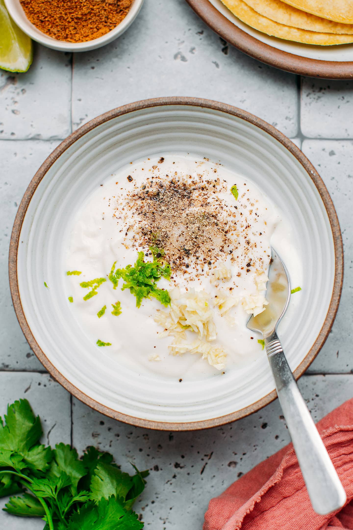 Yogurt, lime zest, pepper, and garlic in a bowl.