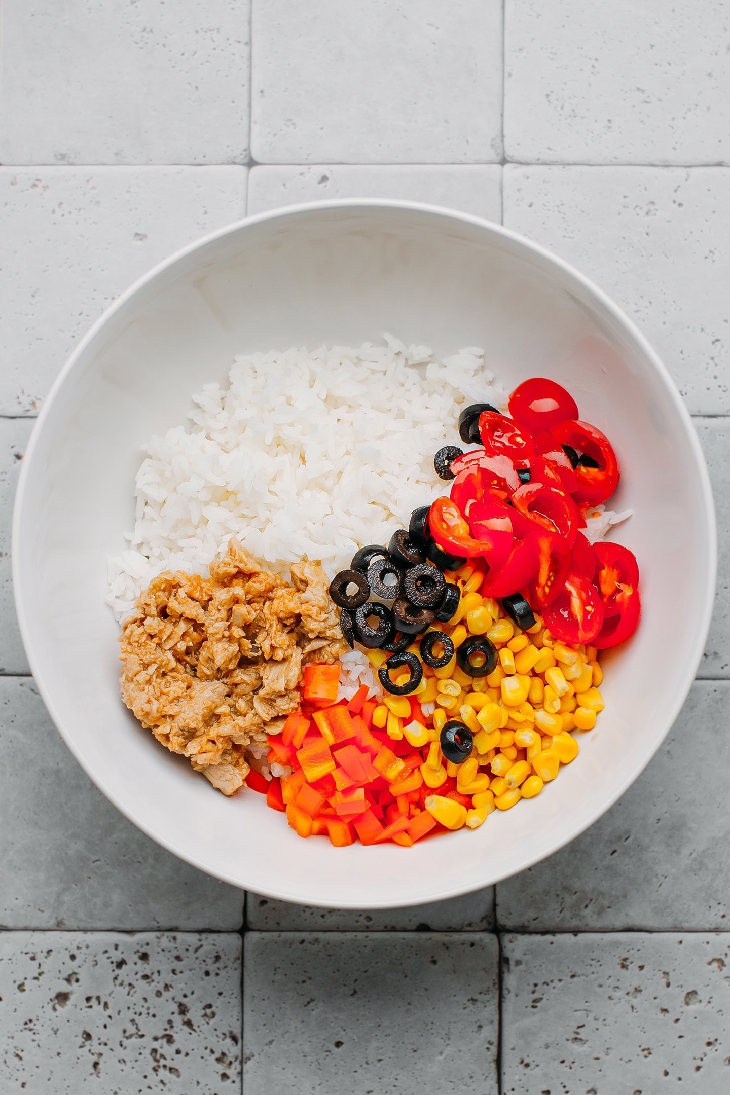 Cooked rice, vegan tuna, corn, and tomatoes in a bowl.