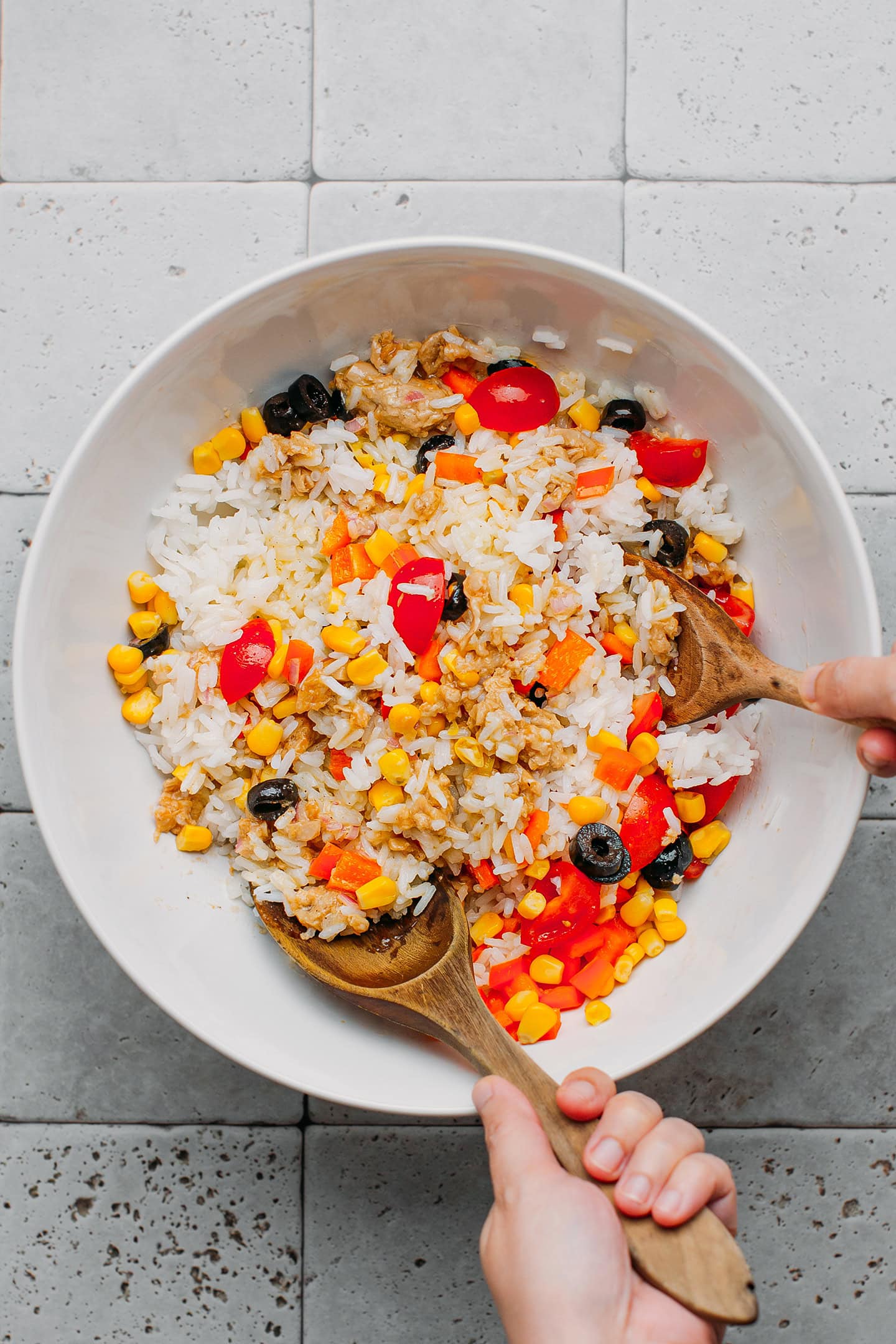 Tossing rice with vegetables and vinaigrette.