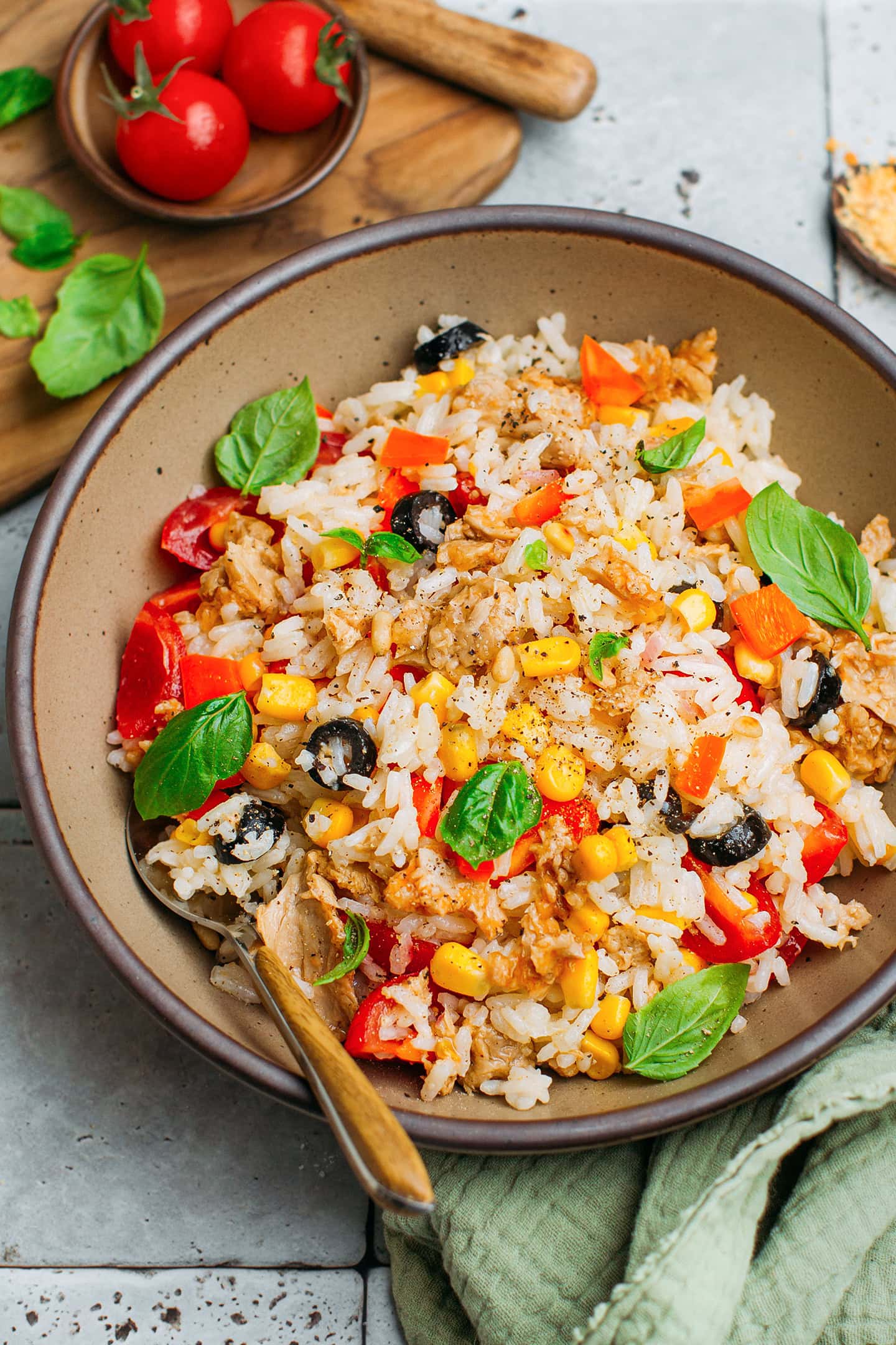 Rice salad with vegan tuna, corn, and olives in a brown bowl.