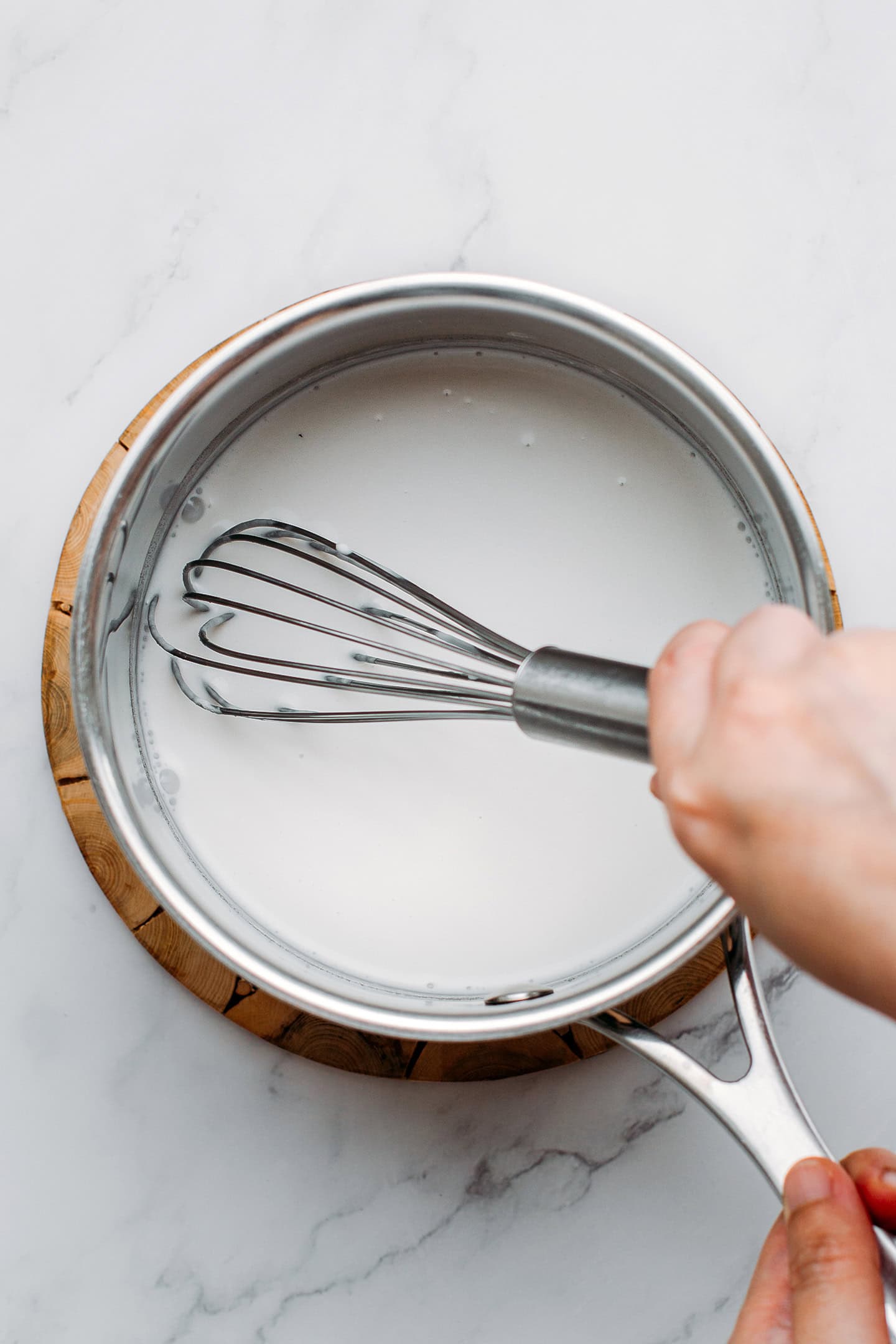 Whisking coconut milk and agar in a saucepan.