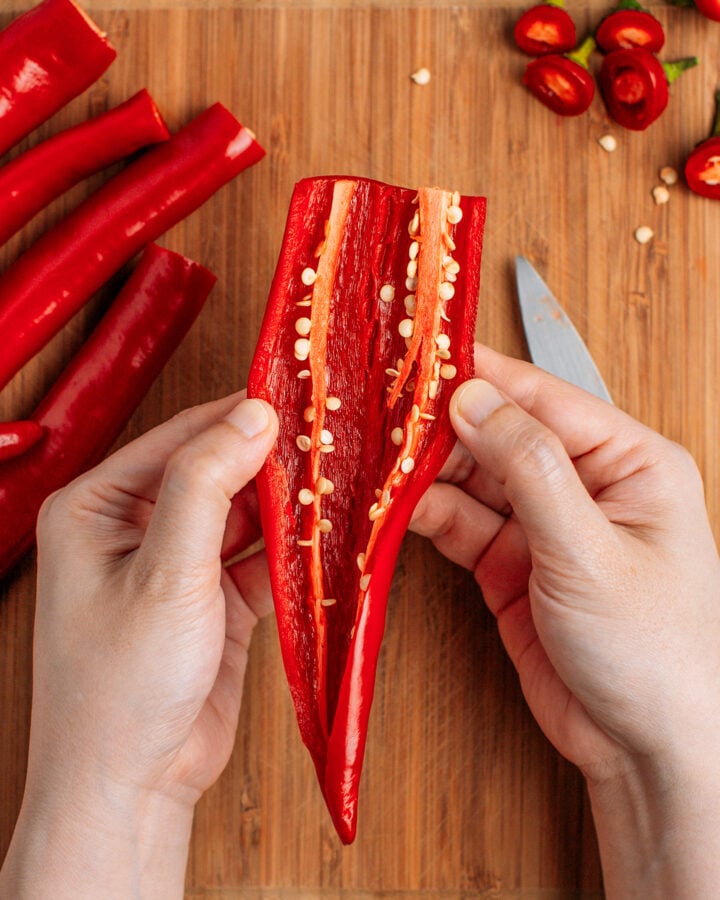 Opening a sliced chili to reveal the seeds.