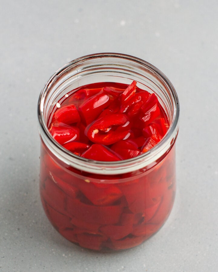 Glass jar filled with chopped cayenne peppers in a brine.