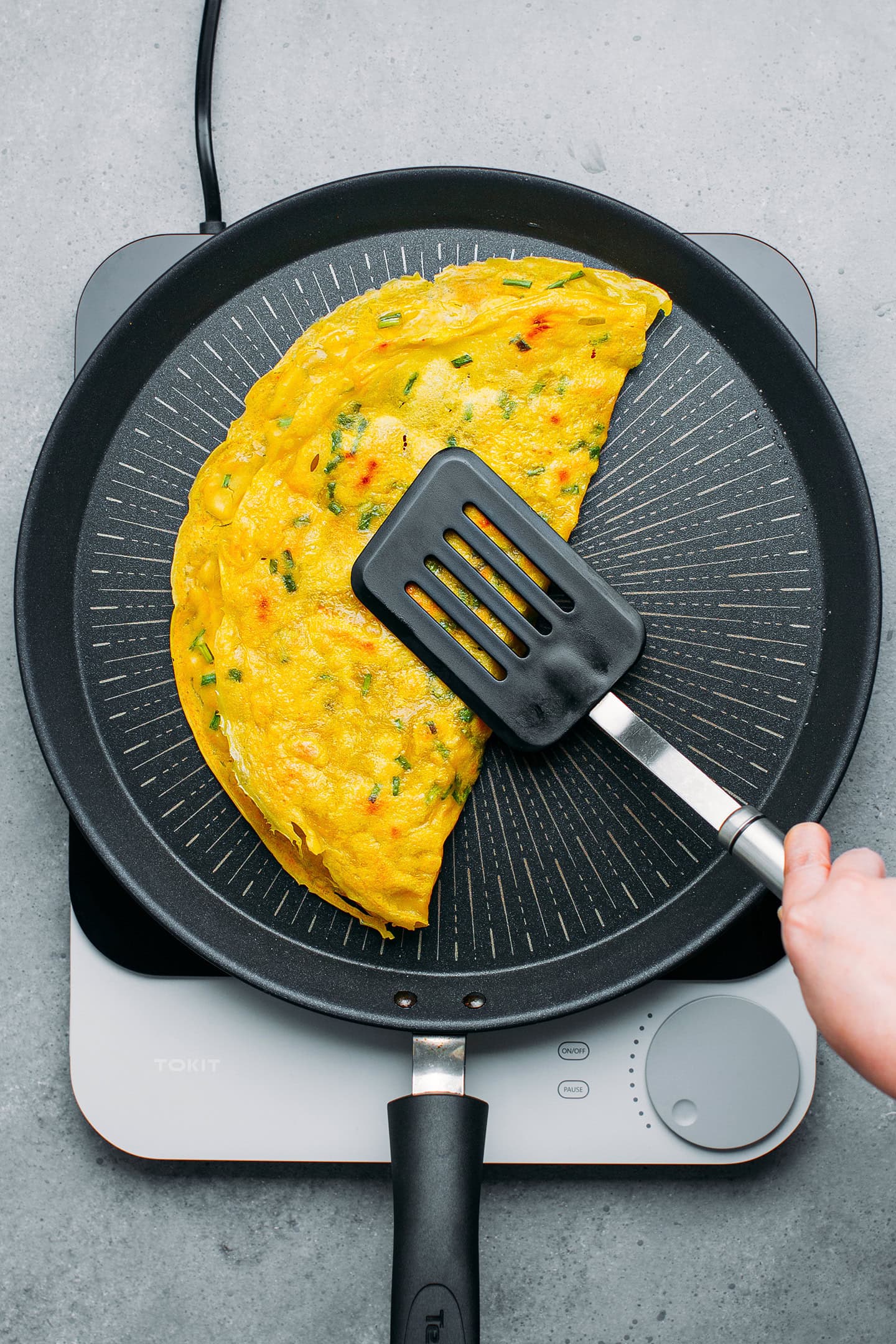 Folding banh xeo in a skillet.