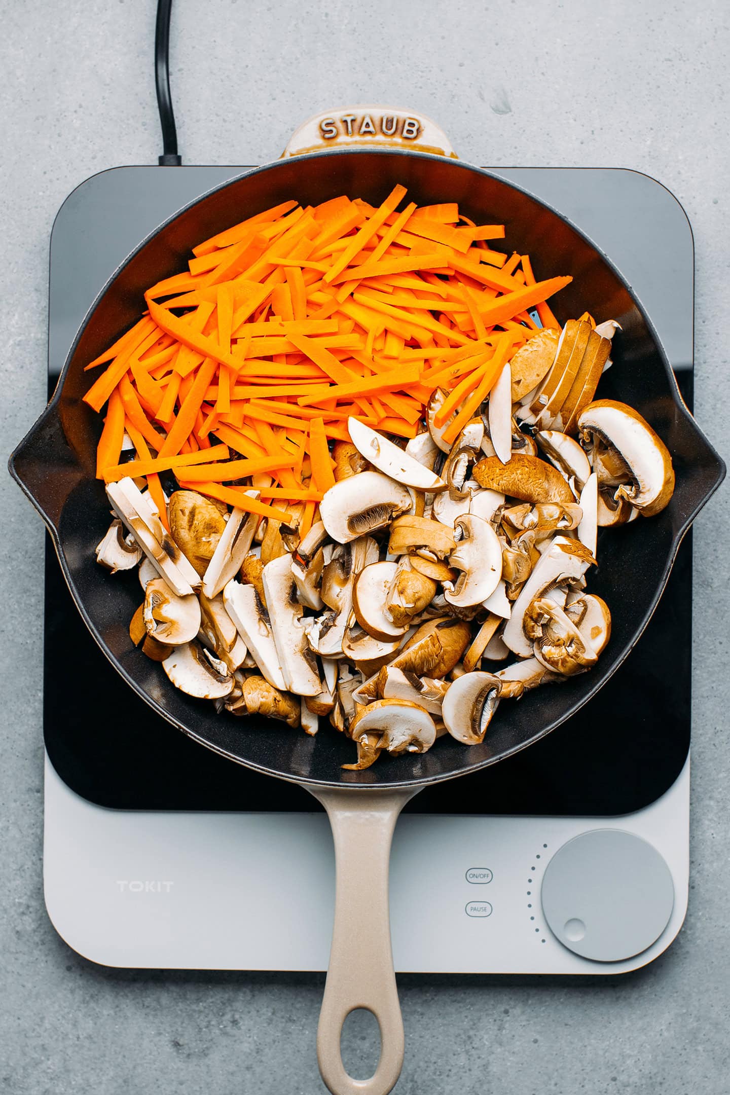 Sliced carrots and mushrooms in a skillet.