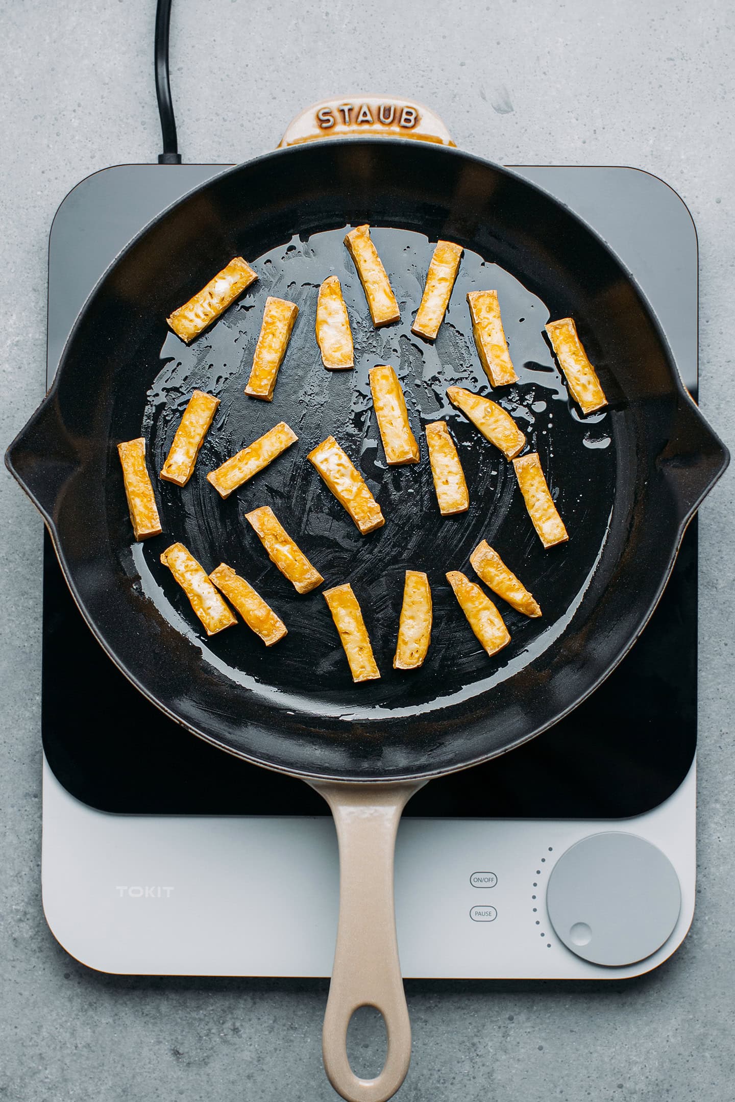 Fried tofu strips in a skillet.