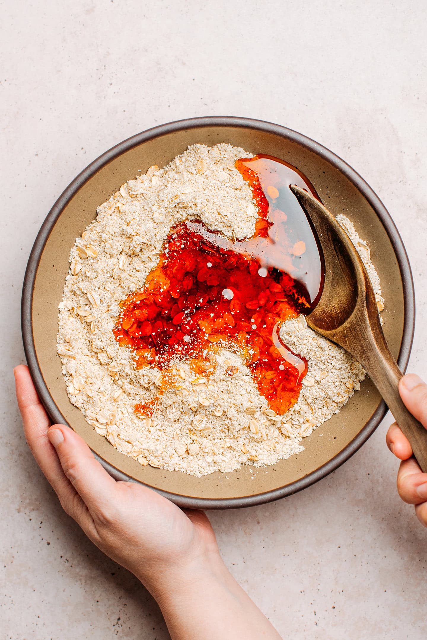 Mixing almond flour, oats, shredded coconut, and coconut nectar in a bowl.