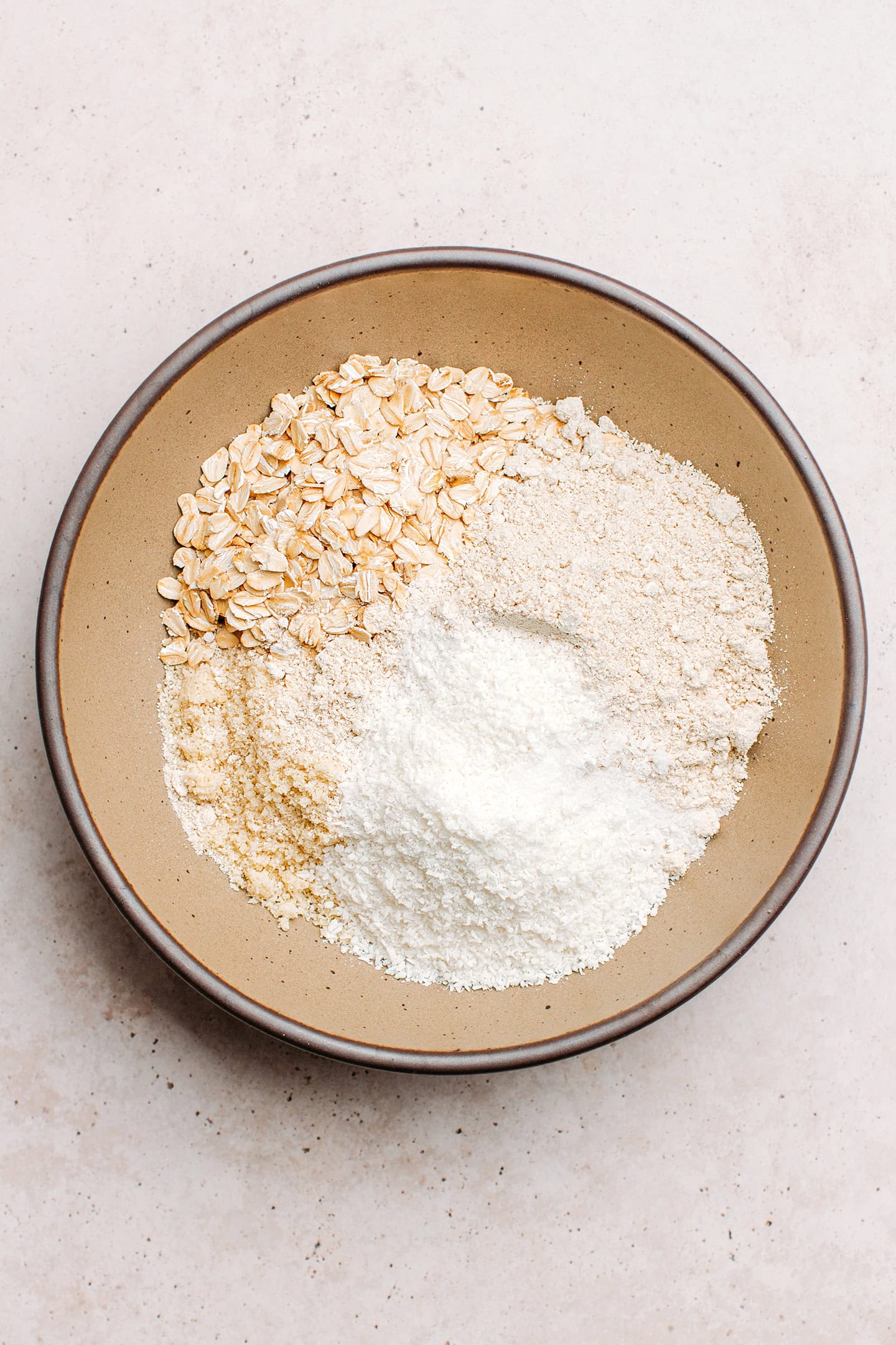 Rolled oats, shredded coconut, and almond flour in a bowl.