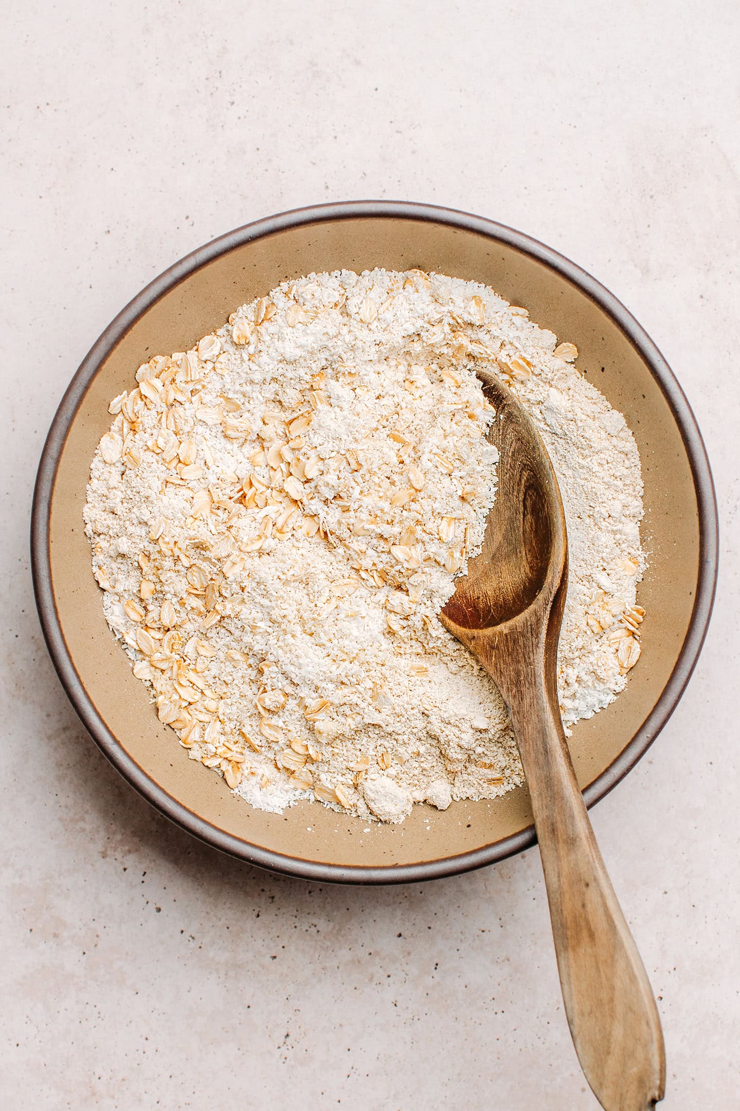 Dry ingredients like rolled oats, shredded coconut, and almond flour in a bowl.