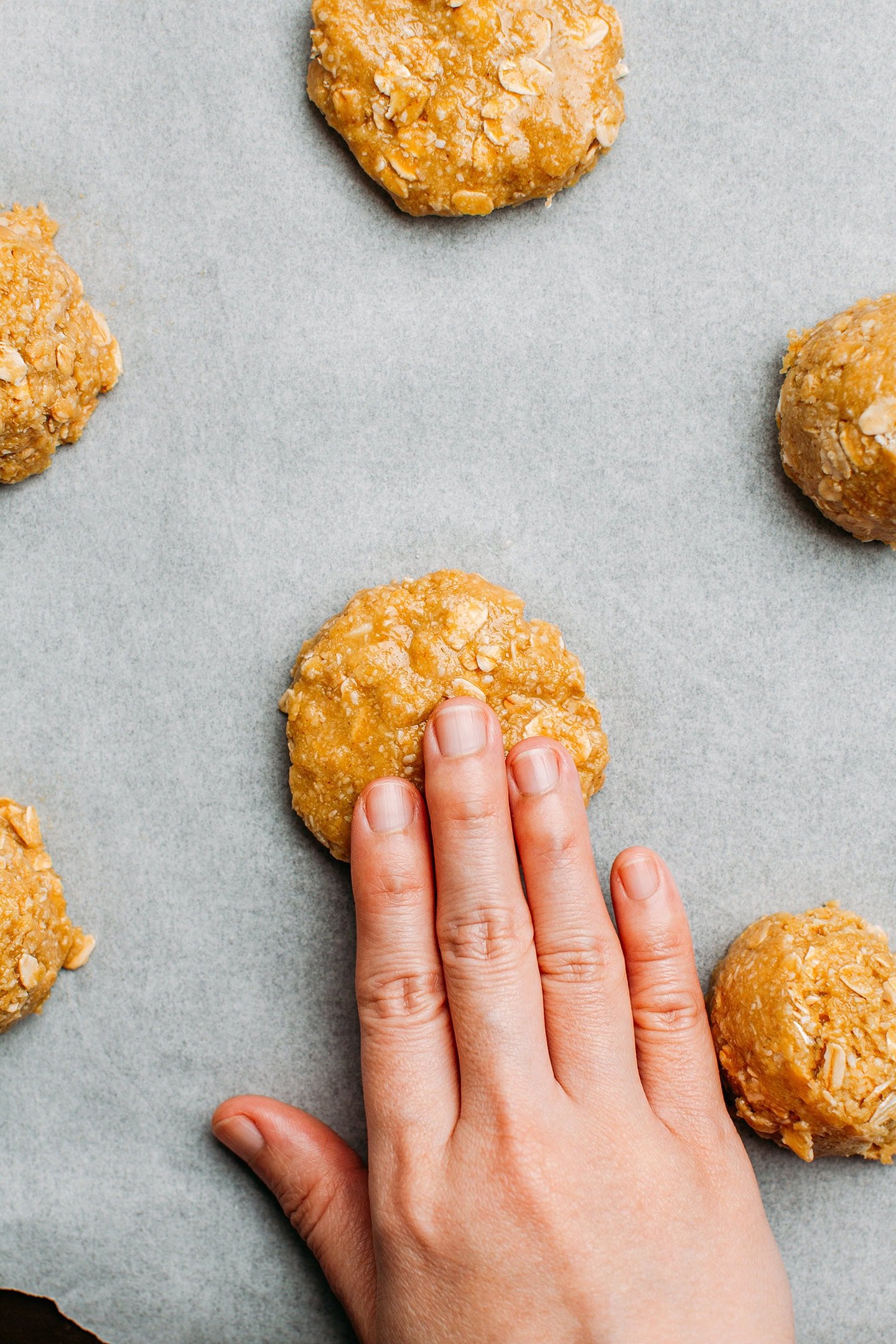 Pressing a ball of cookie dough on a baking sheet.