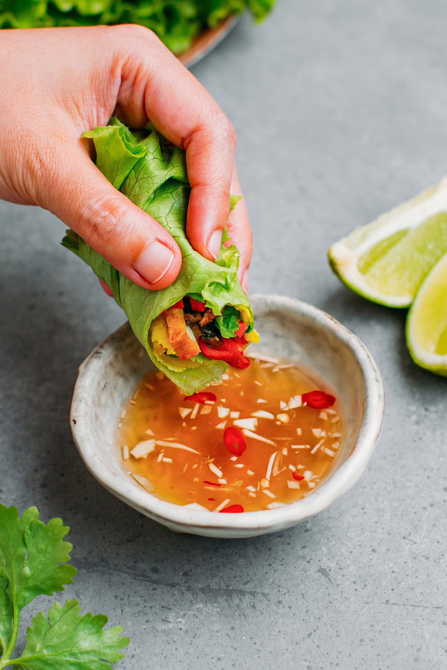 Dipping bánh xèo wrapped in lettuce in a dipping sauce.