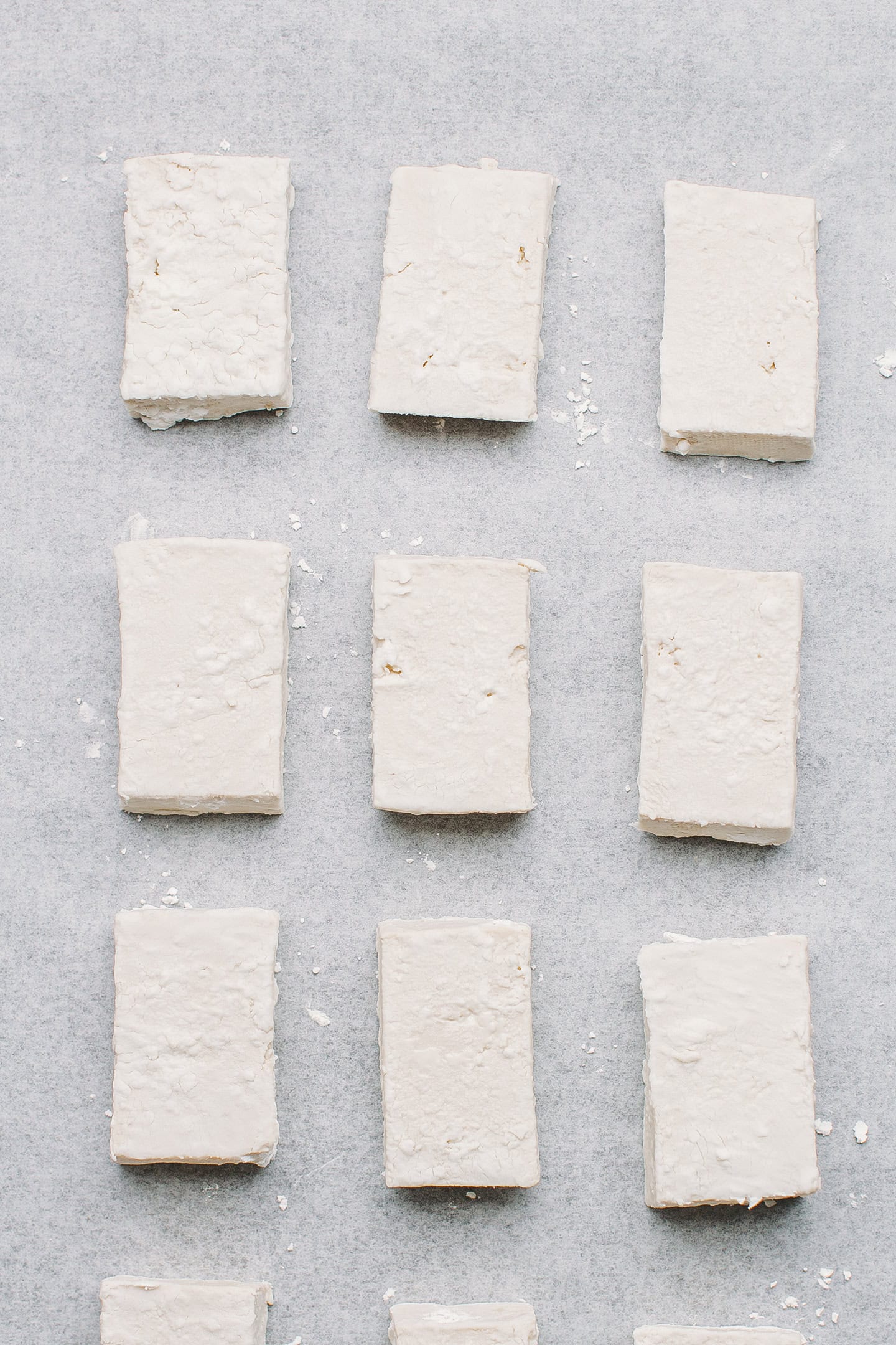 Tofu coated with cornstarch on a baking sheet.