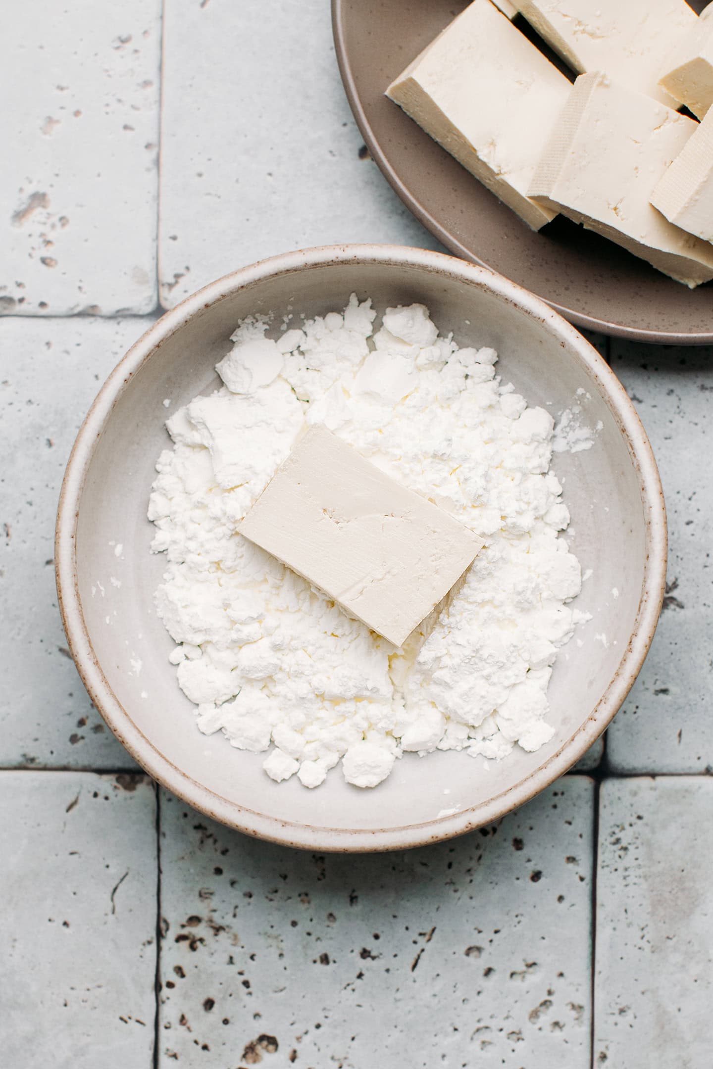 Piece of tofu in a bowl of cornstarch.