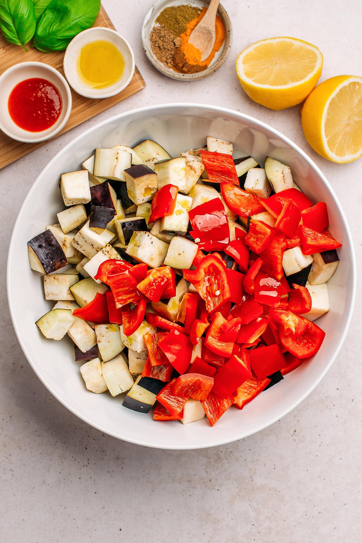 Diced eggplant and red bell pepper in a mixing bowl.