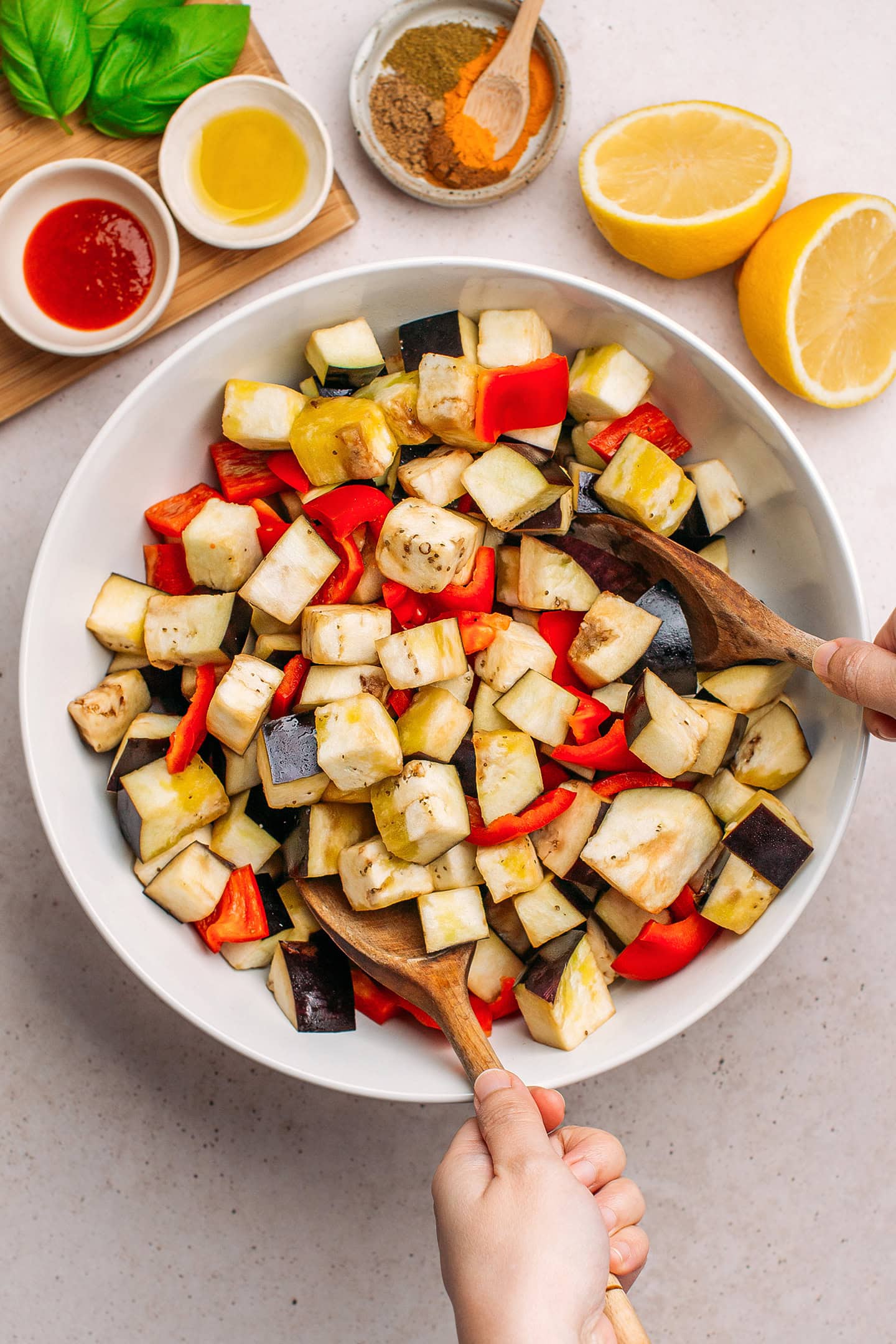 Tossing diced eggplant and bell pepper with olive oil.