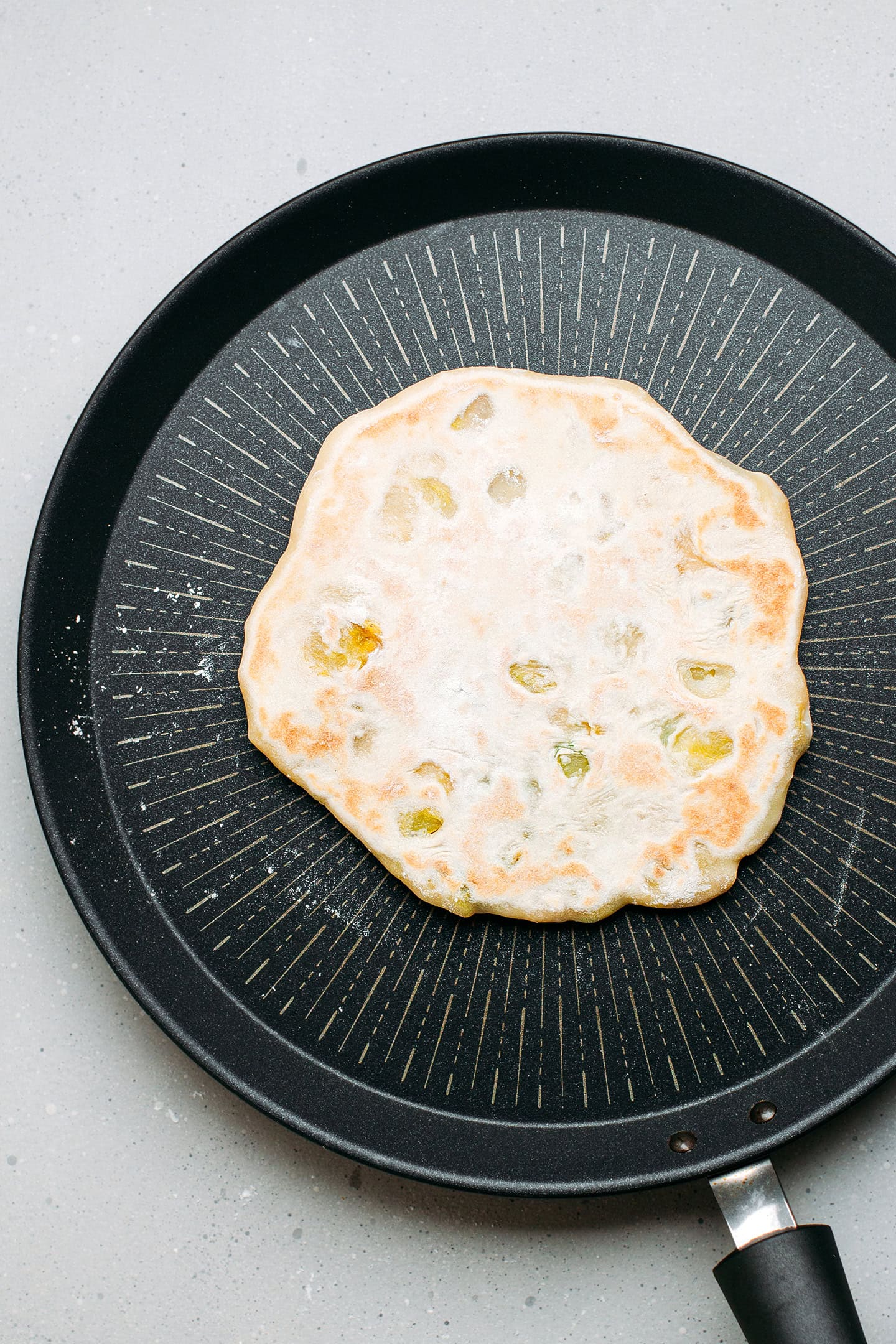 Cooked naan on a non-stick skillet.