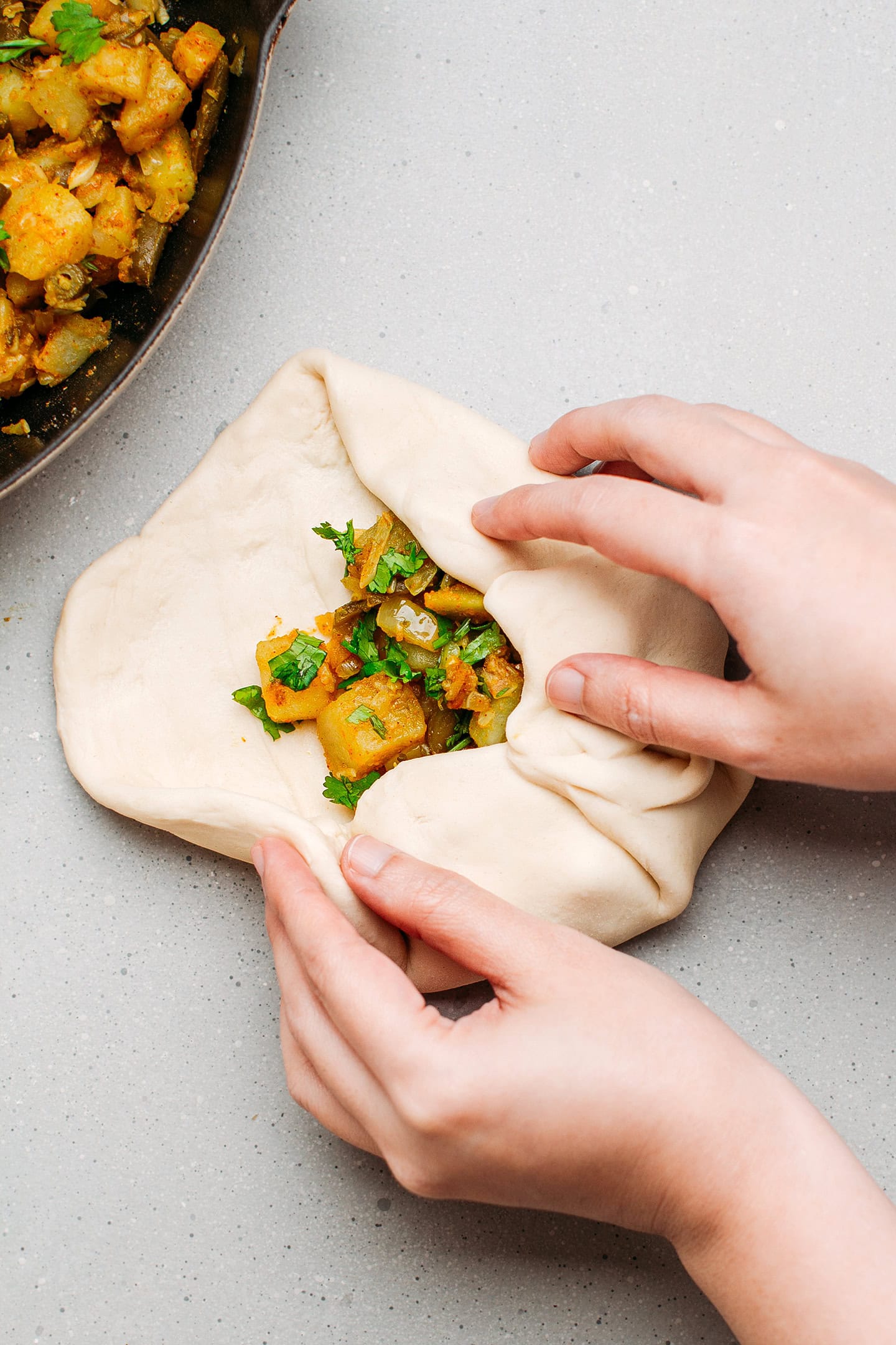 Wrapping potato filling with dough.