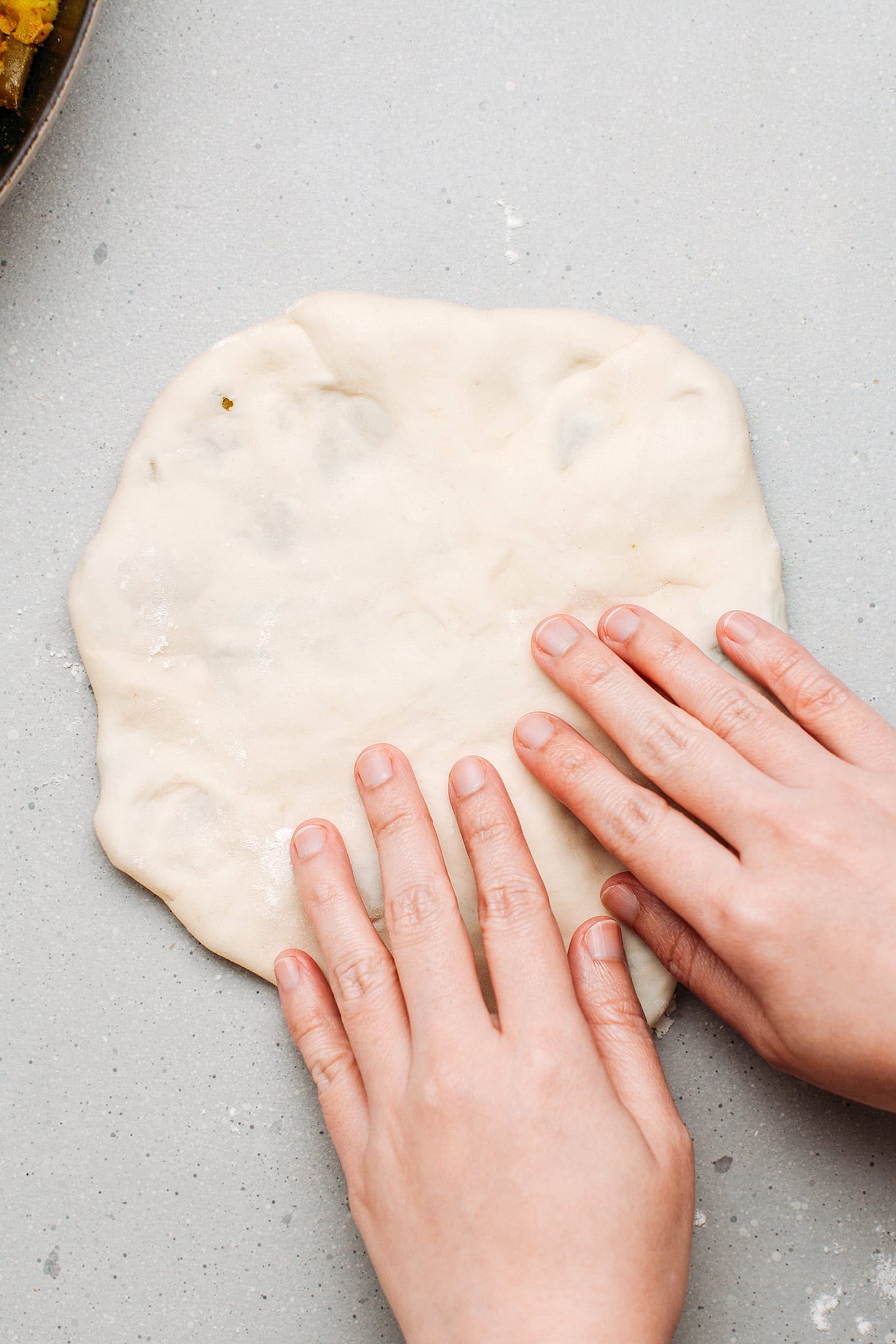 Flattening a dough filled with potato and green beans.