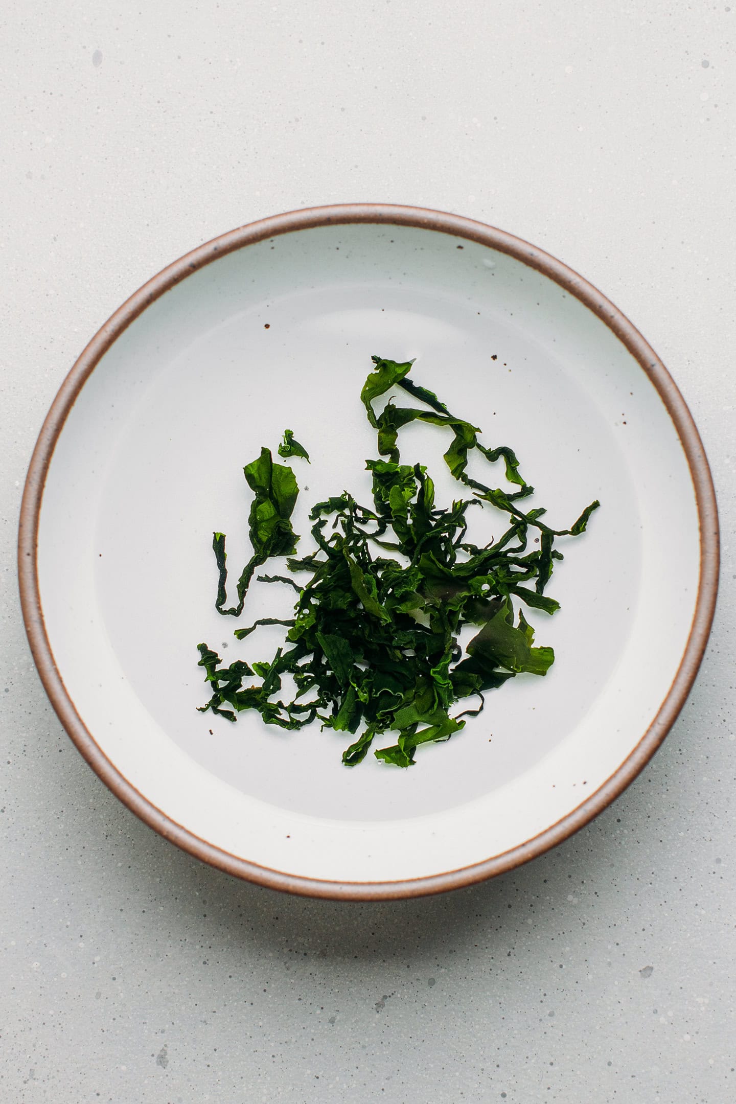 Dried wakame in a bowl of water.