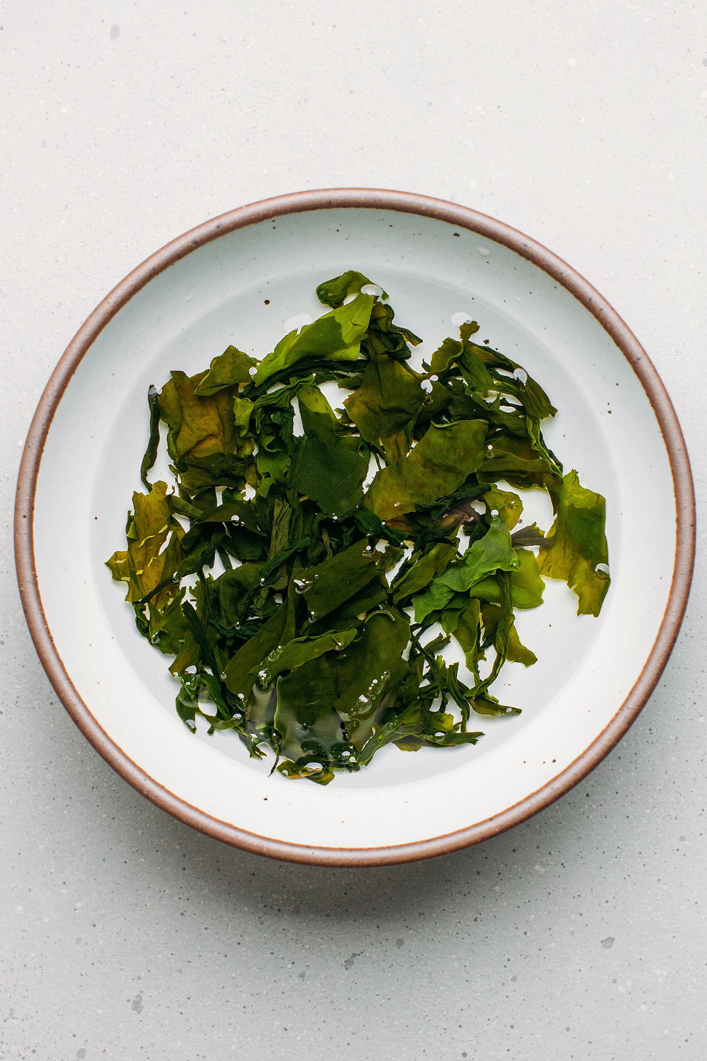 Rehydrated wakame in a bowl of water.