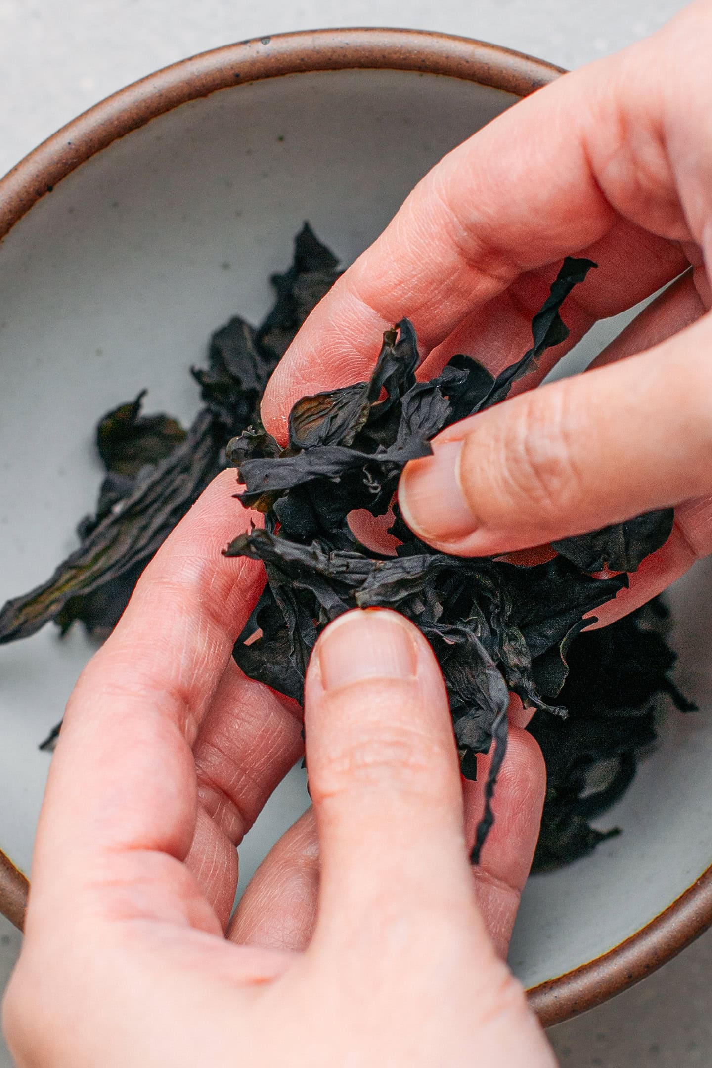 Crushing dried wakame using hands.