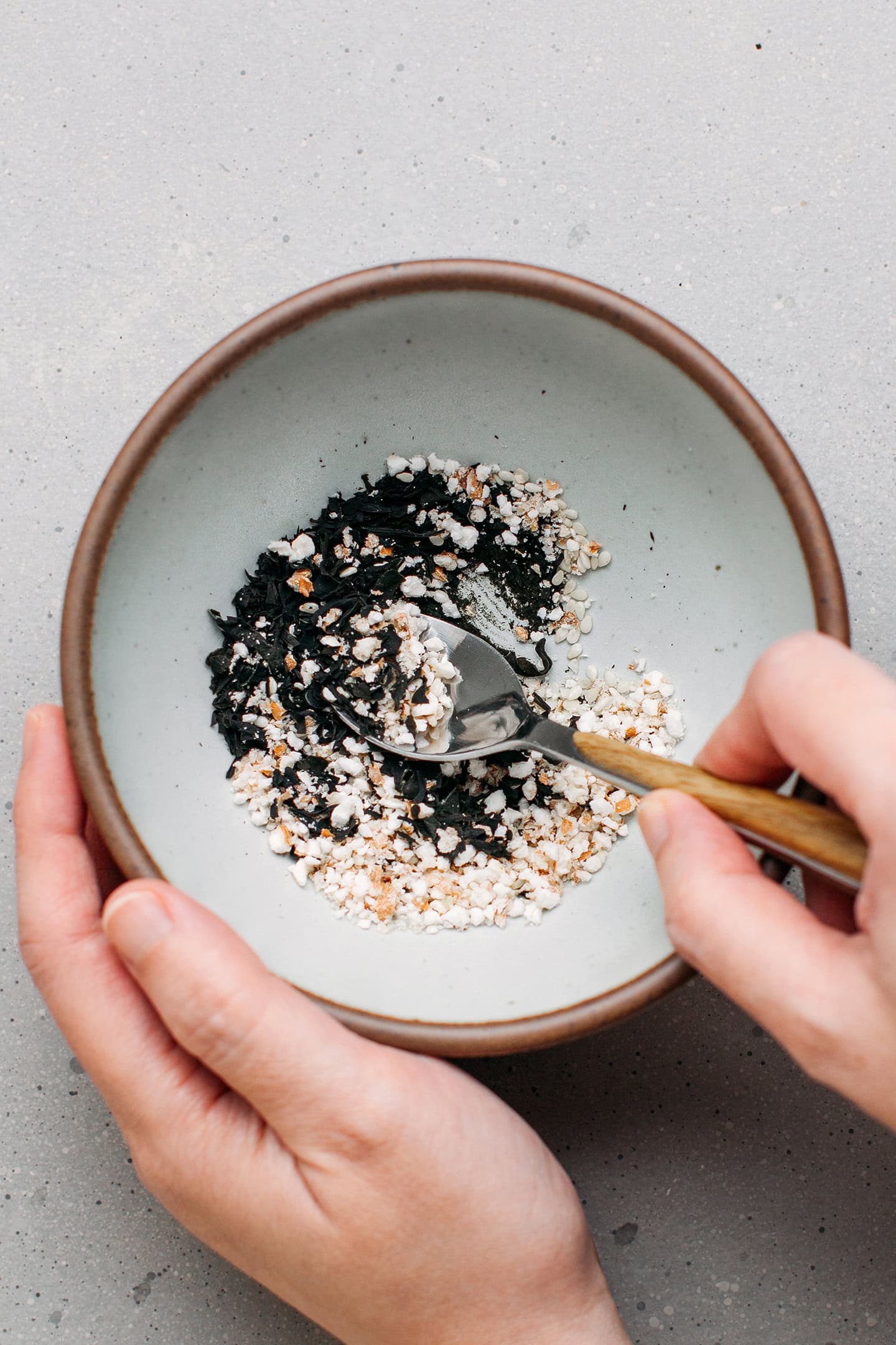 Stirring dried wakame with sesame seeds and puffed cereals.