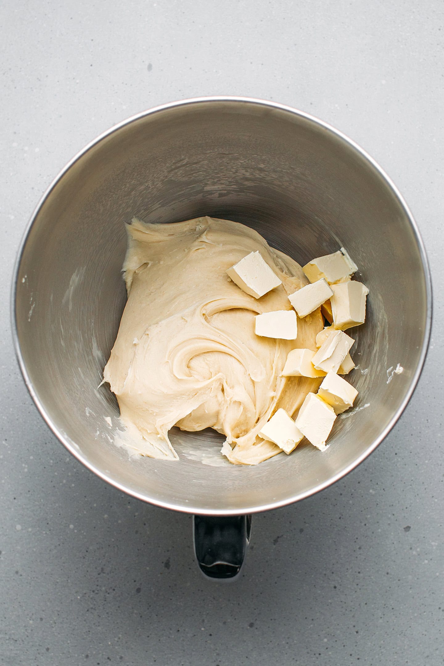 Dough and cubed butter in the bowl of a stand mixer.