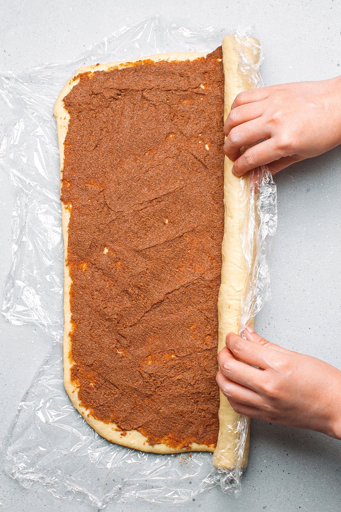 Rolling brioche dough filled with cinnamon sugar.