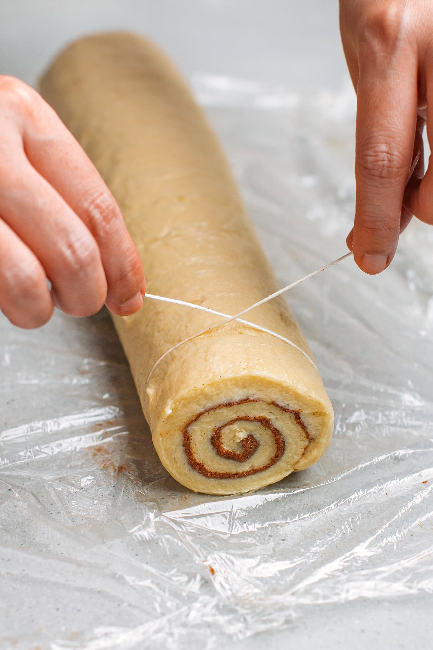 Slicing an unbaked cinnamon roll using dental floss.