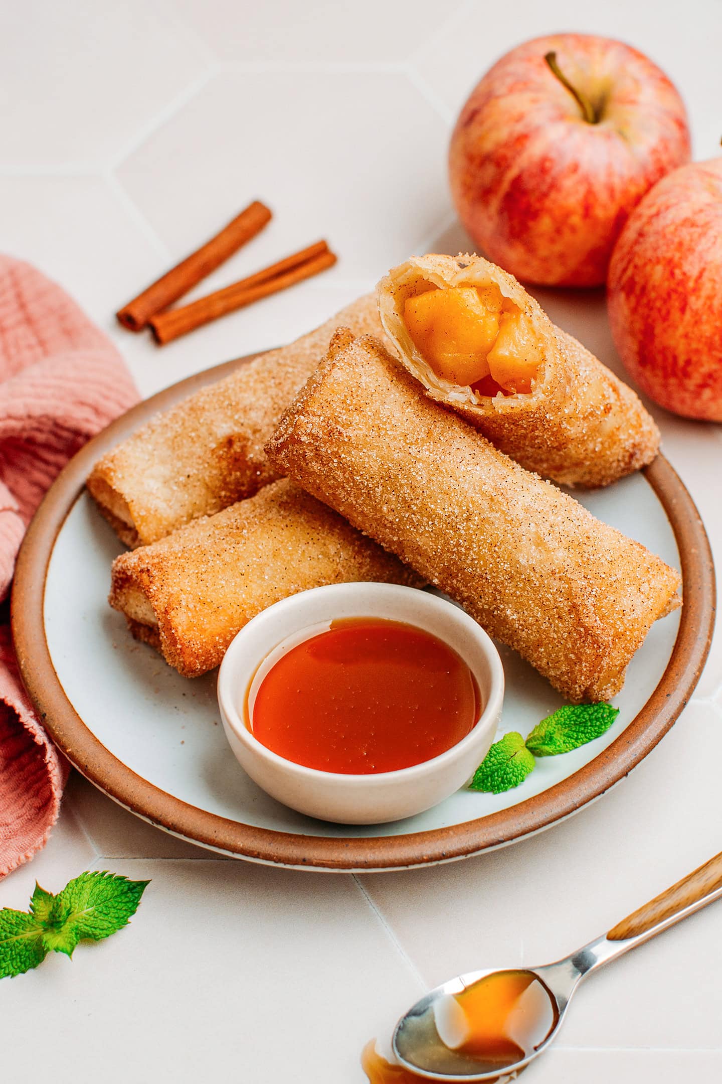 Egg rolls filled with apples on a serving plate.