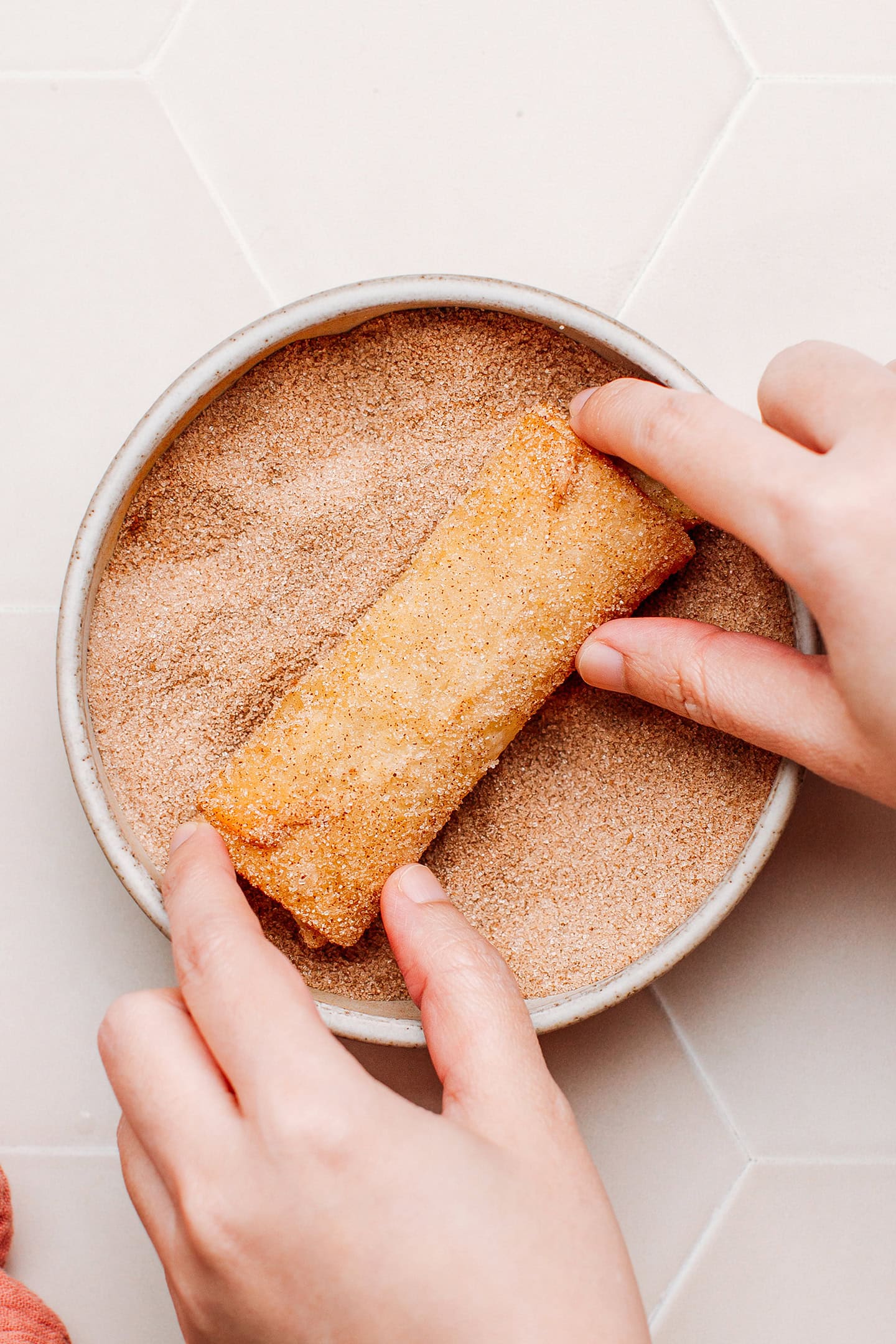 Tossing an egg roll with cinnamon sugar.