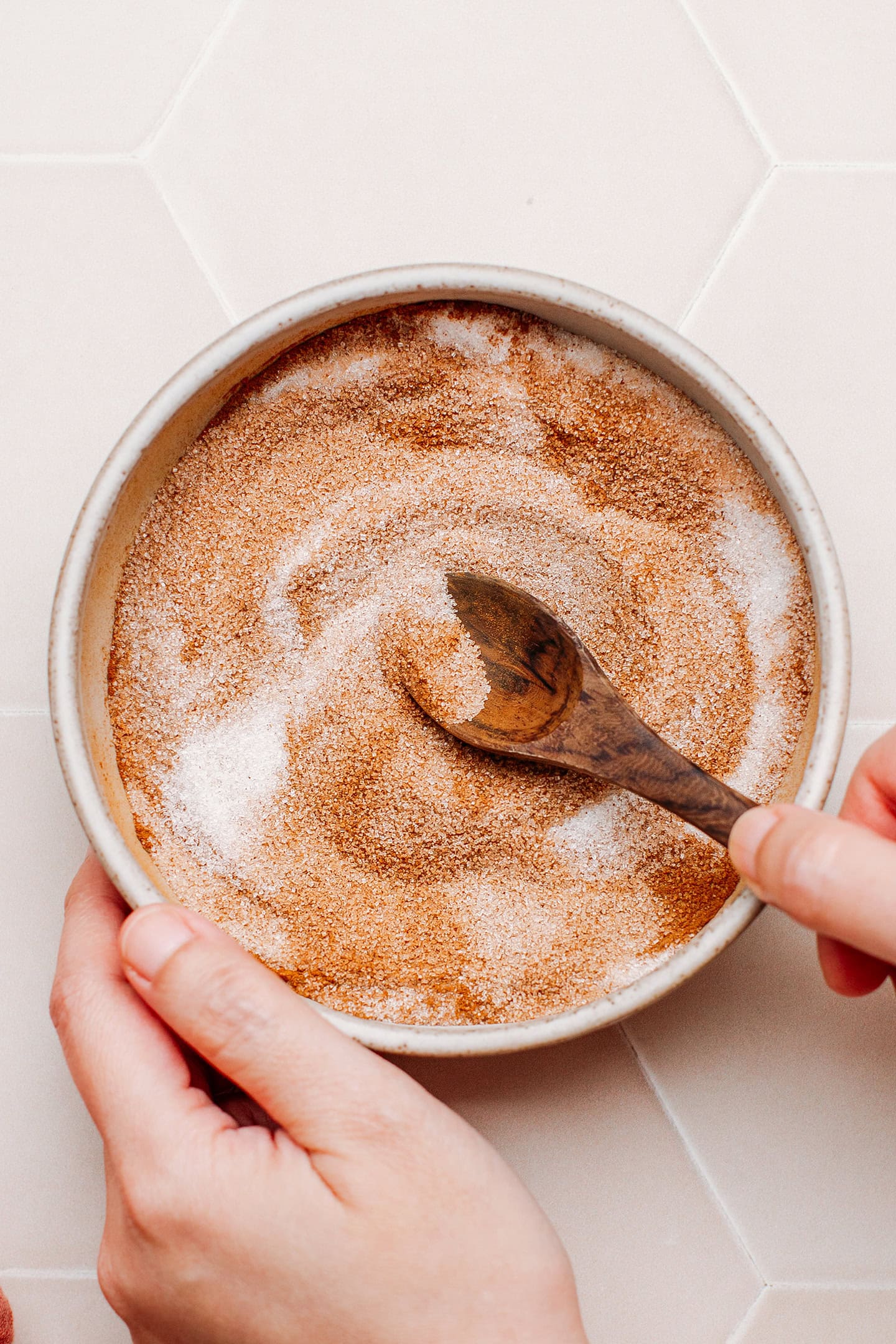 Stirring sugar with ground cinnamon in a small bowl.