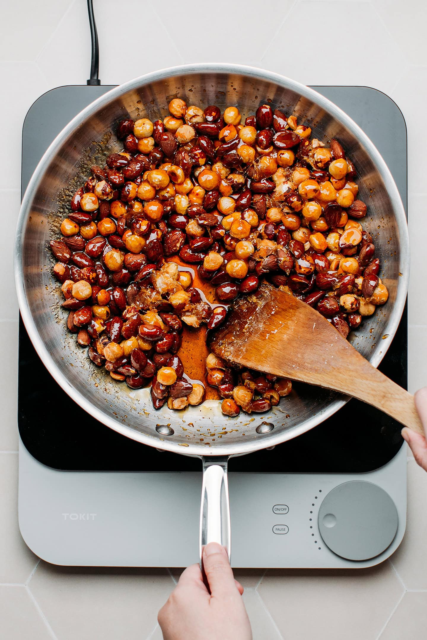 Coating hazelnuts and almonds with caramel in a pan.