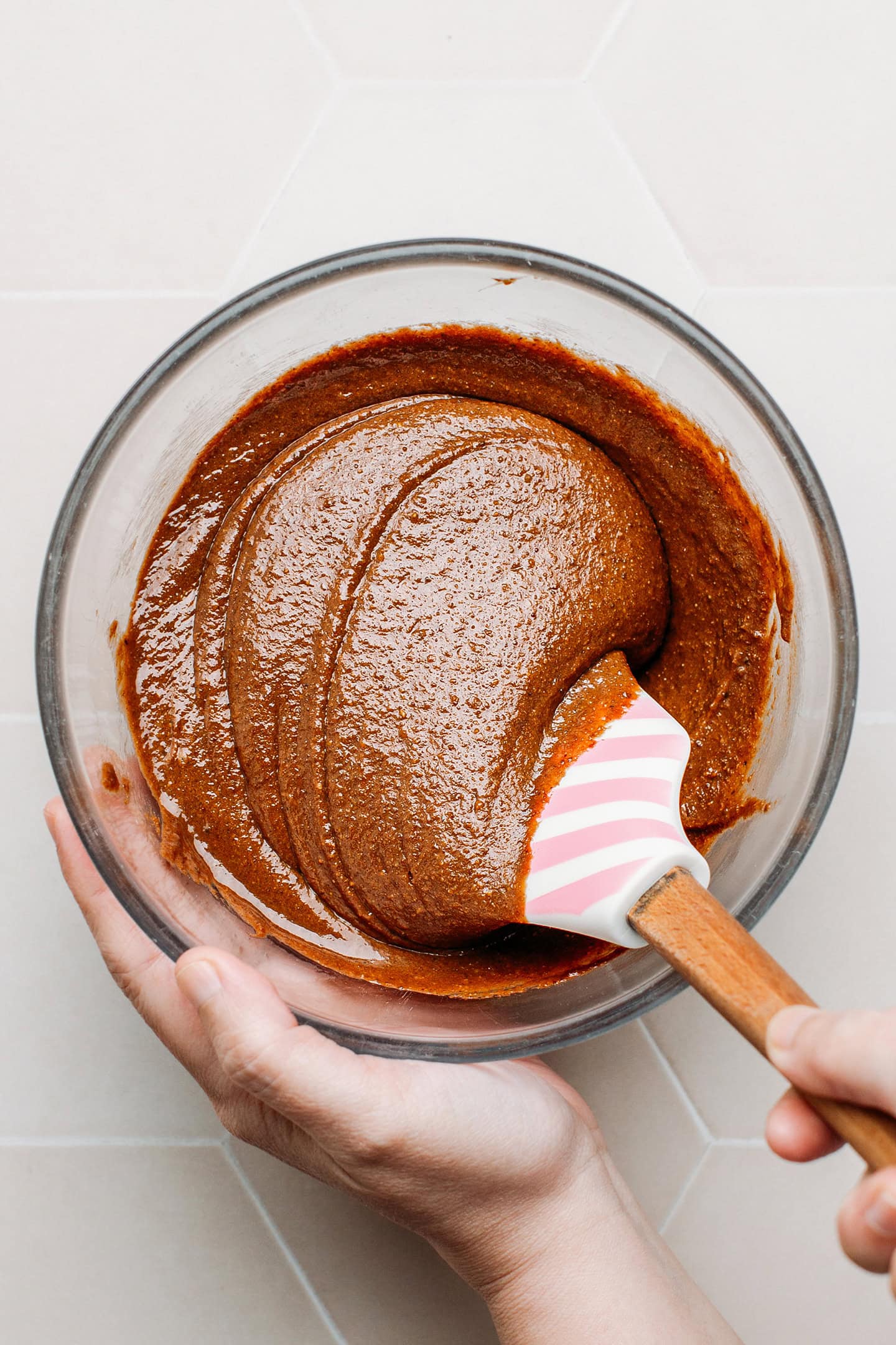 Mixing praline paste and melted dark chocolate in a bowl.