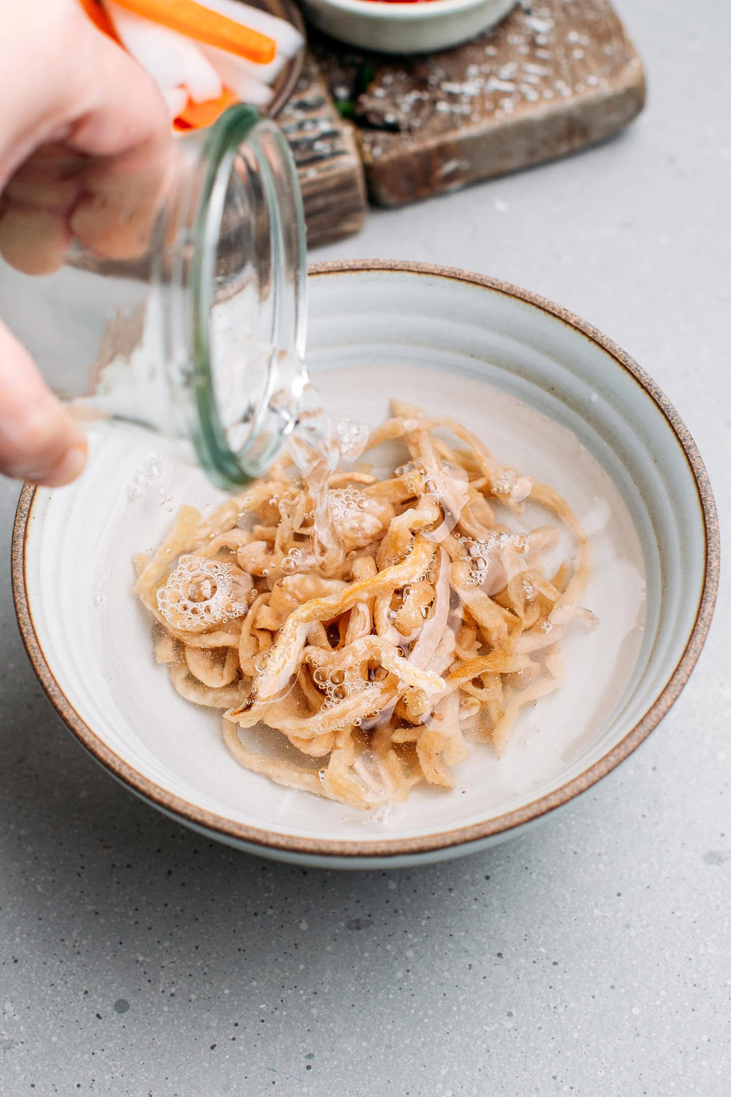 Pouring water into a bowl containing preserved radish.