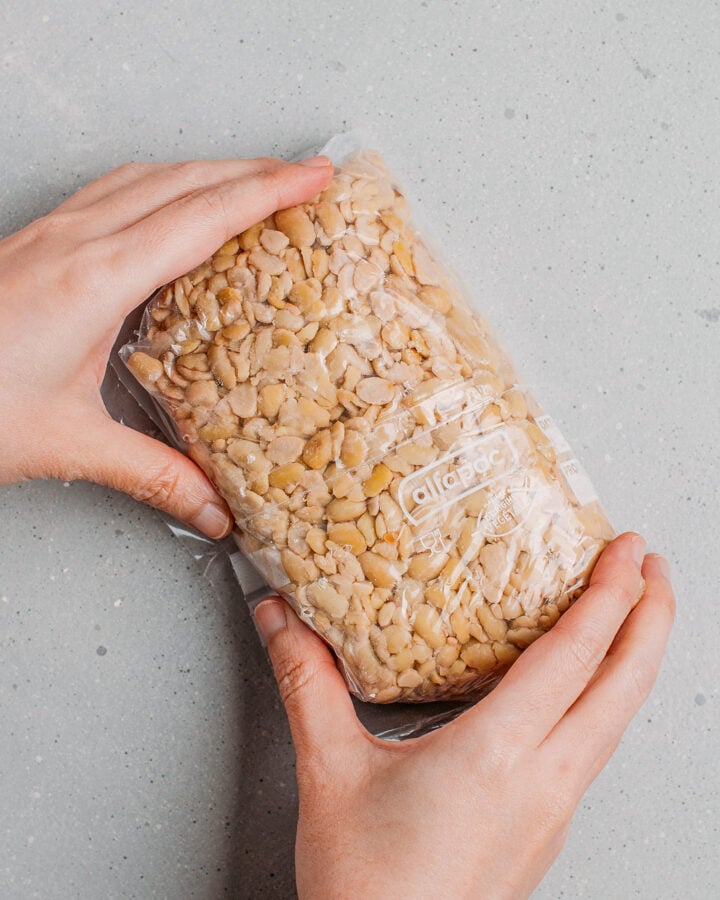 Shaping a freezer bag filled with cooked soybeans into a rectangle loaf.