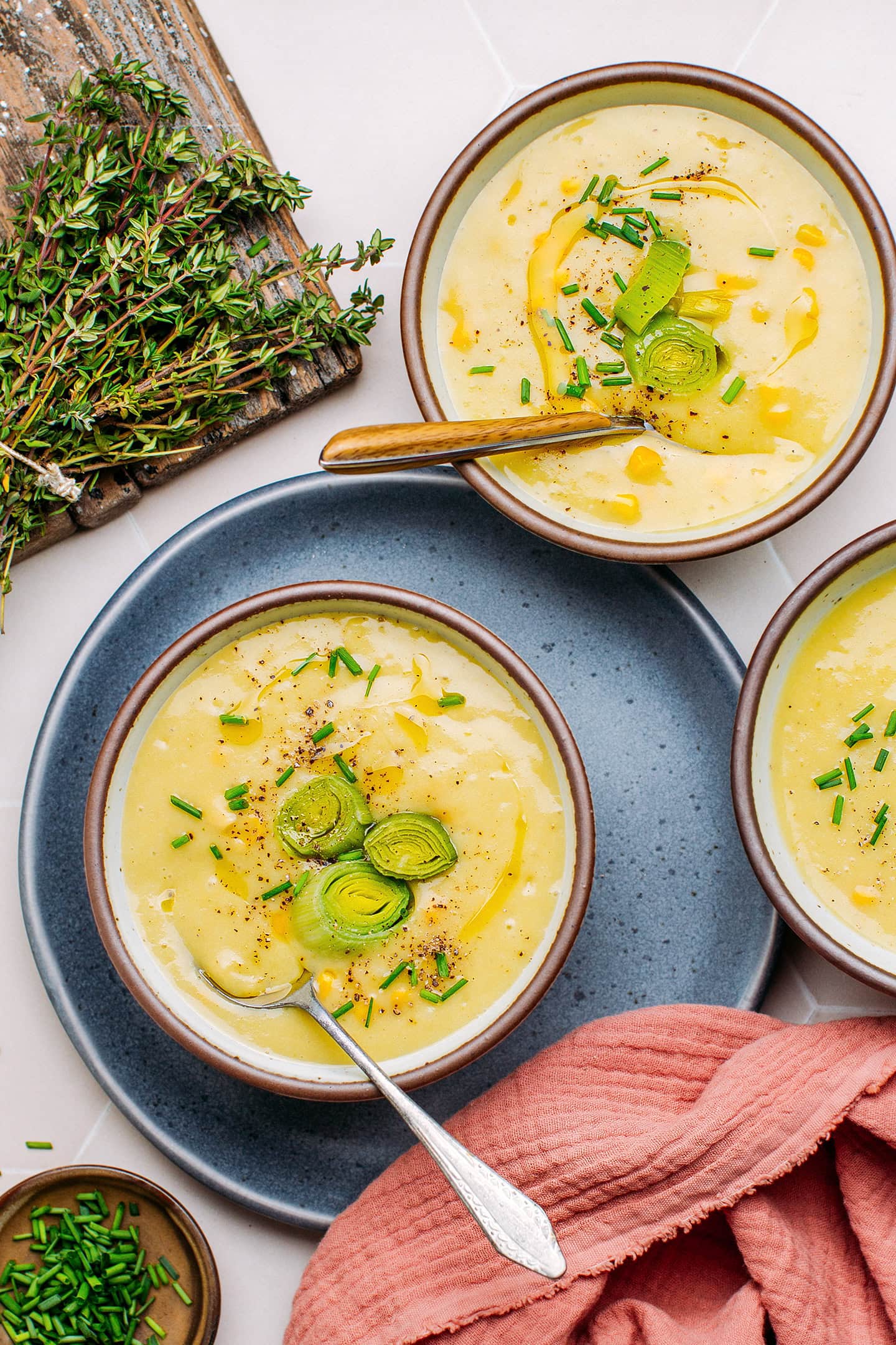 Two bowls of potato leek soup topped with sautéed leeks and chives.