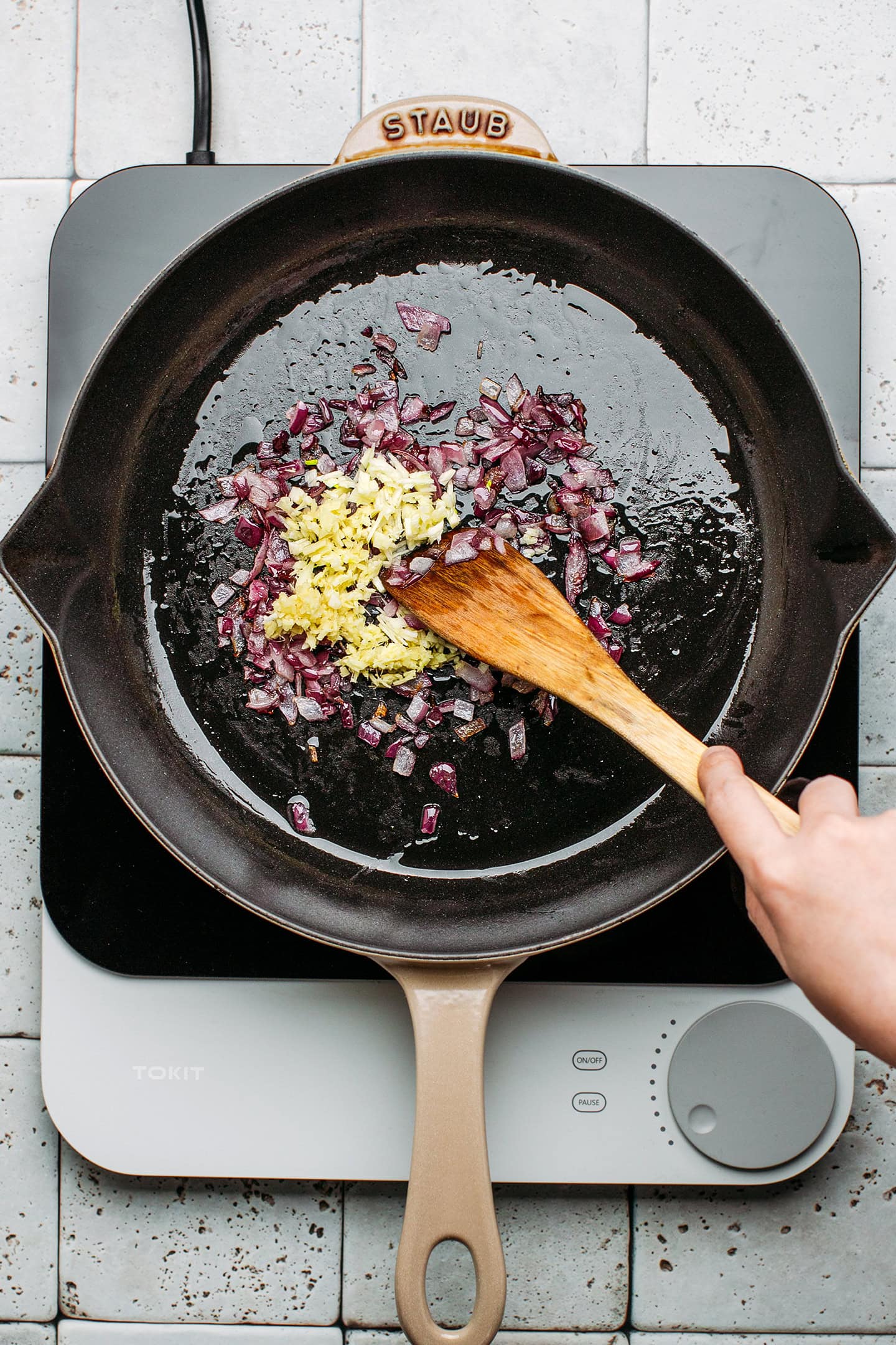 Diced red onion, minced garlic, and ginger in a pan.