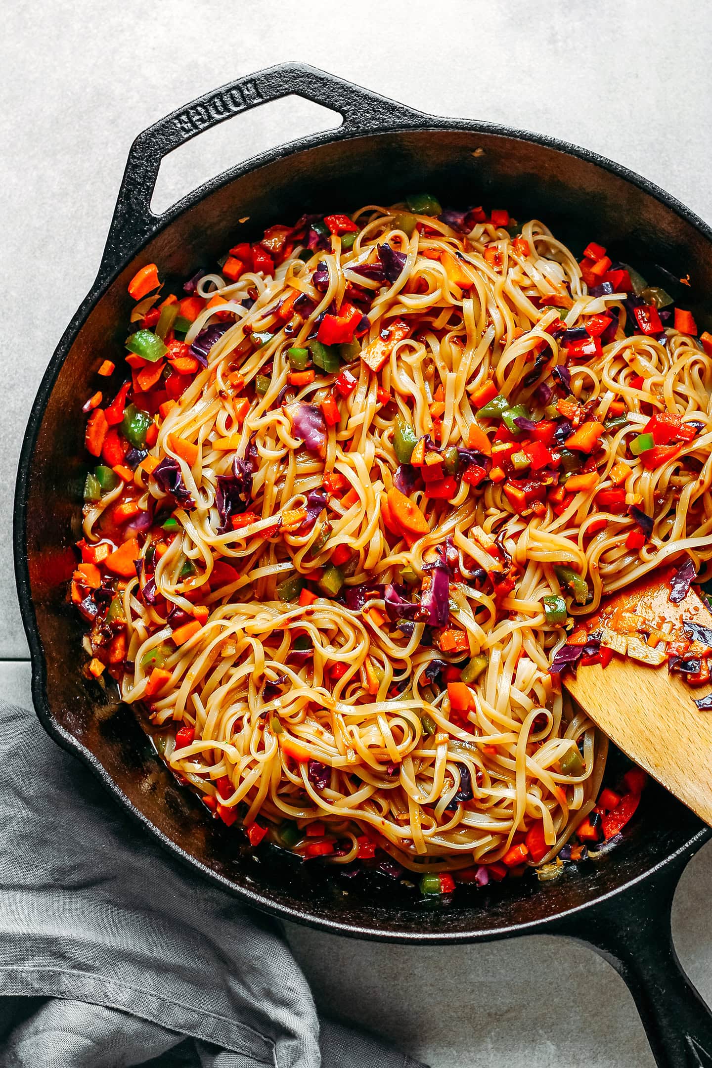 Sautéed noodles with diced vegetables in a skillet.