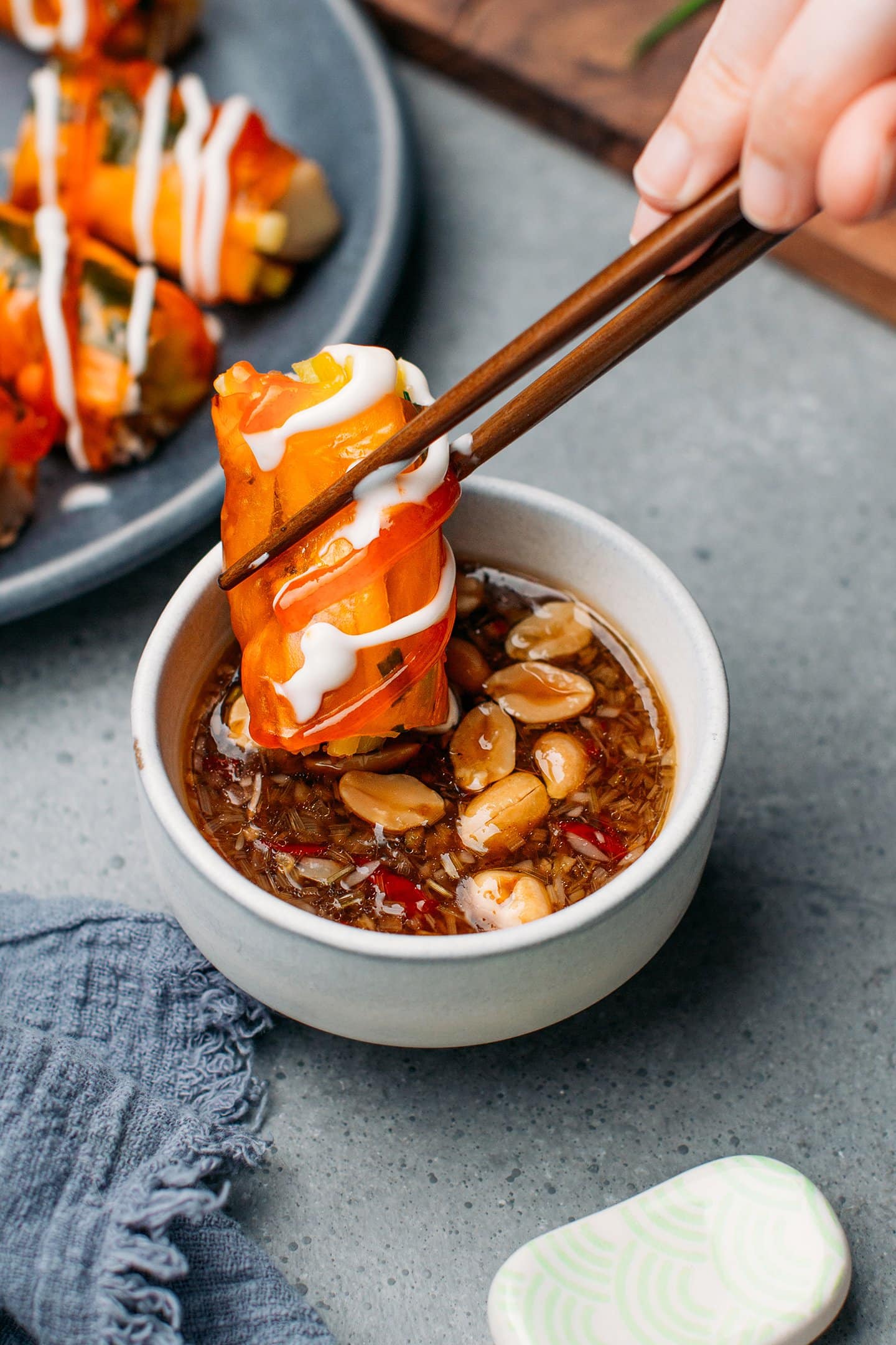 Dipping a rice paper roll into a bowl containing tamarind sauce.