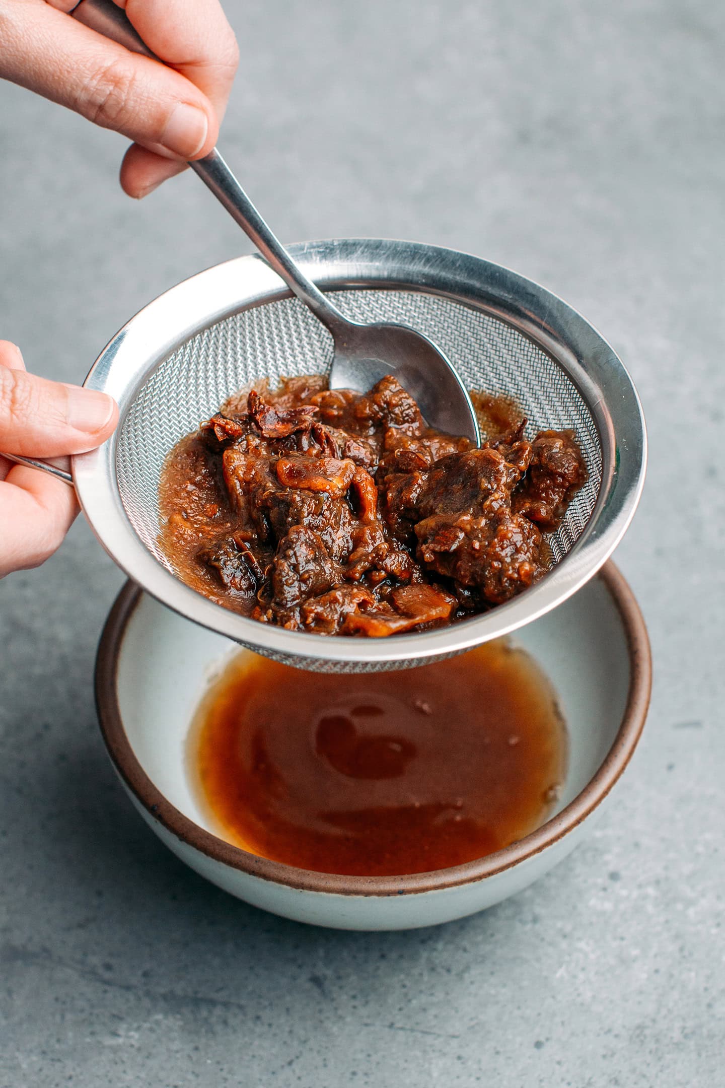 Straining tamarind paste using a fine sieve mesh.