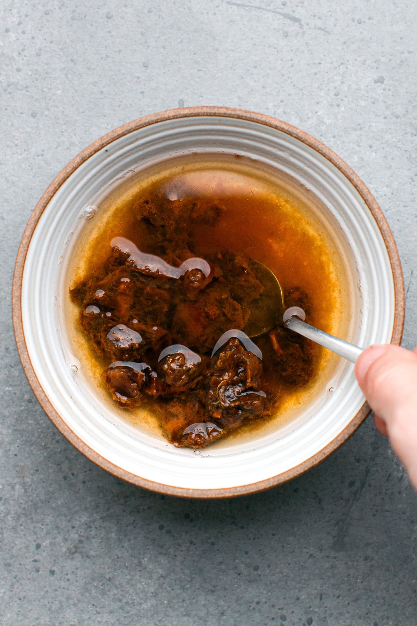 Stirring tamarind paste and water in a bowl.