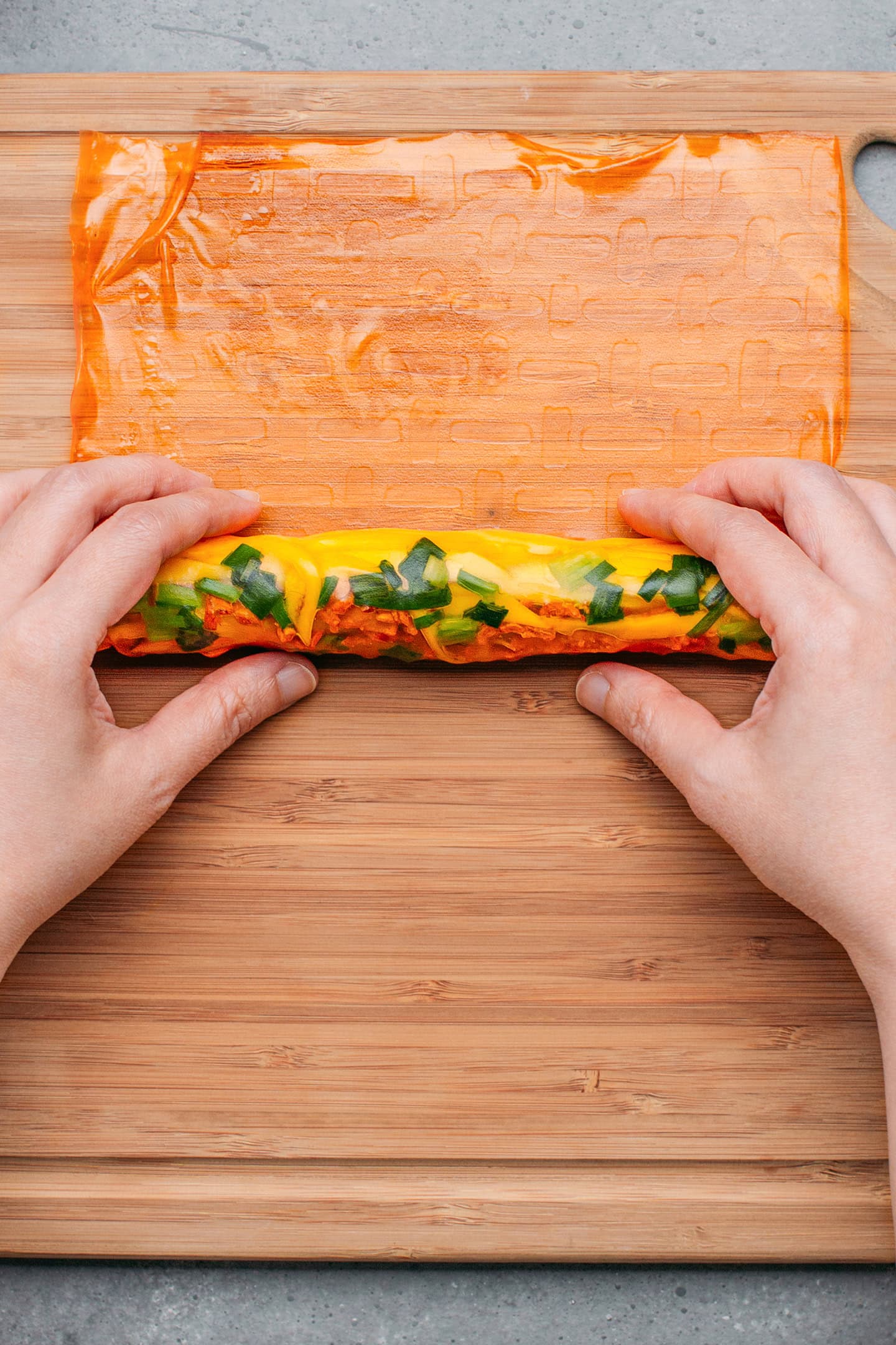 Rolling a rice paper sheet filled with vegetables.