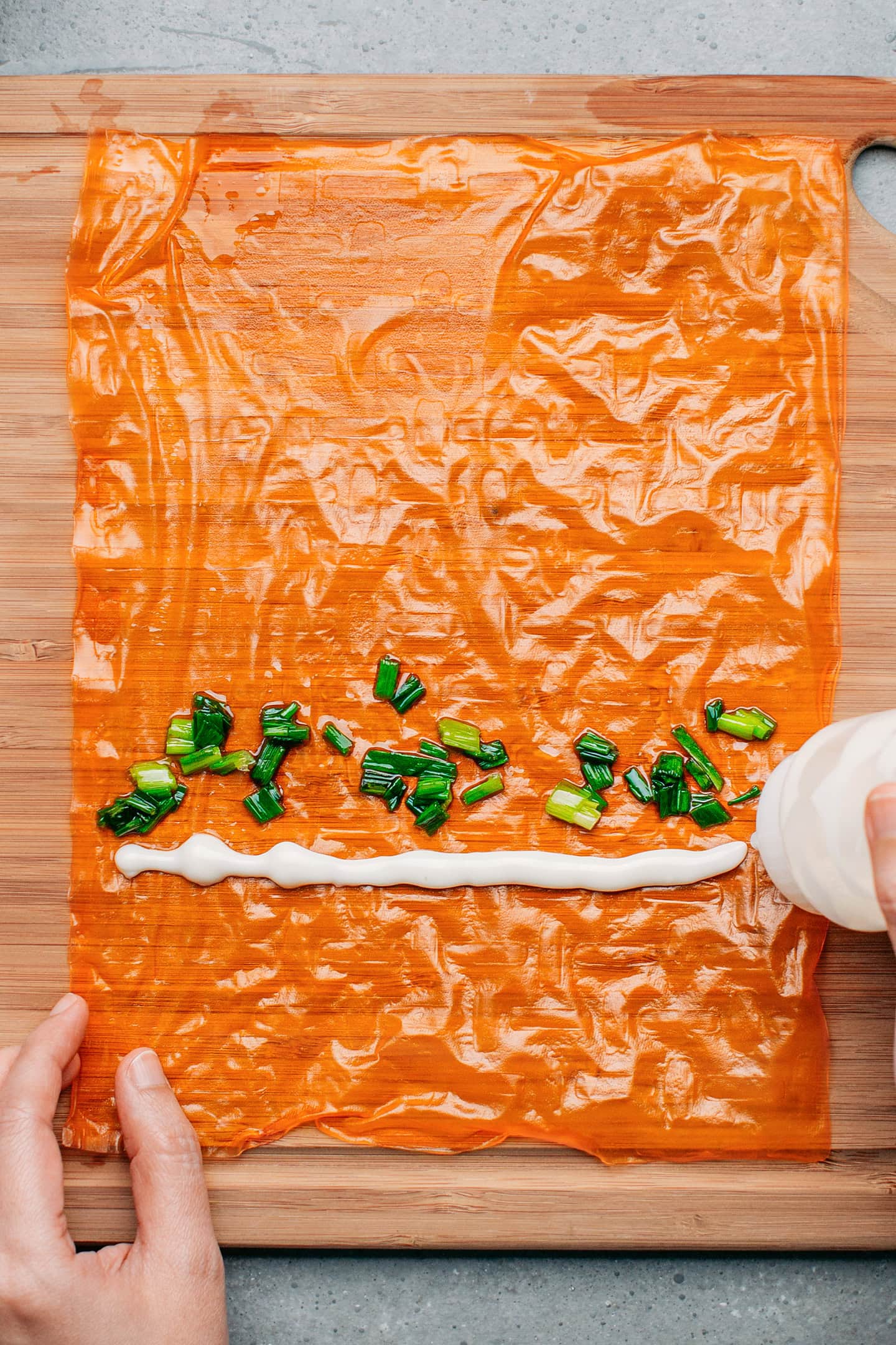 Drizzling mayo on a rice paper sheet.