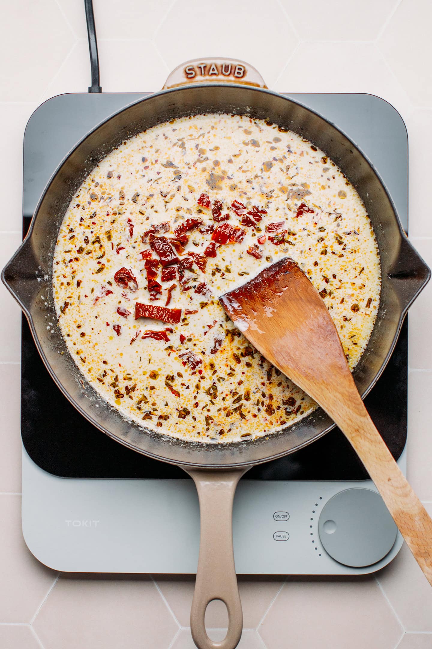 Vegetable broth, dried tomatoes, and cashew cream in a skillet.