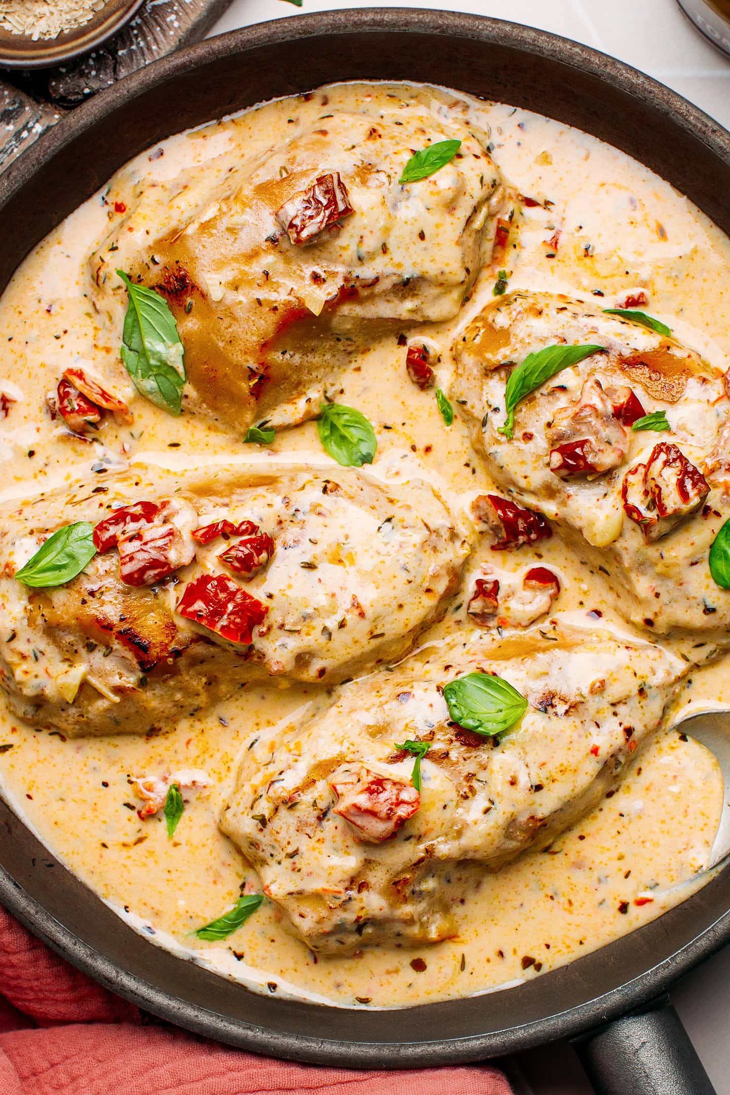 Four pieces of vegan chicken cooked in a creamy sauce in a skillet.