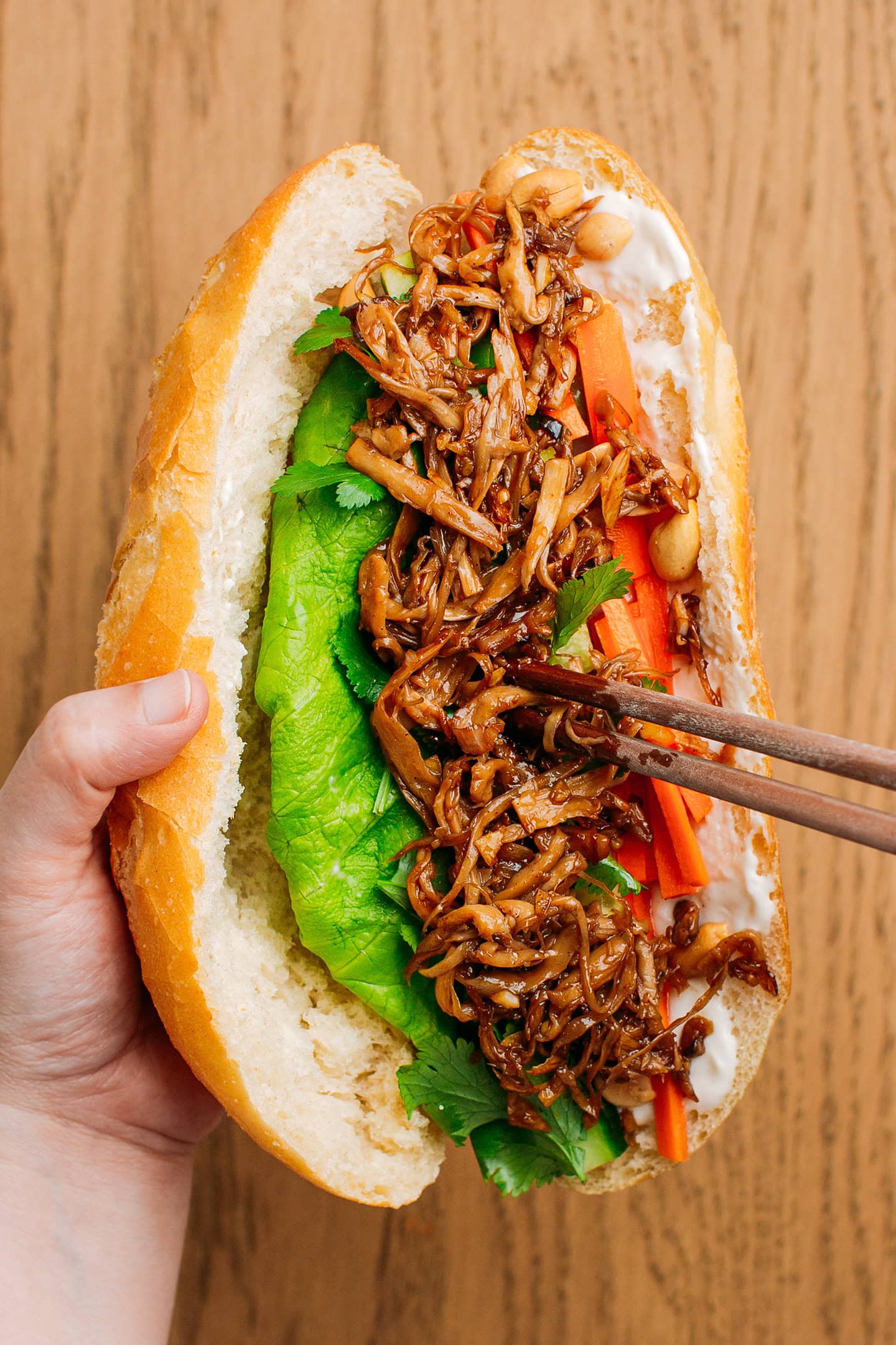 Adding pulled mushrooms to a banh mi sandwich.