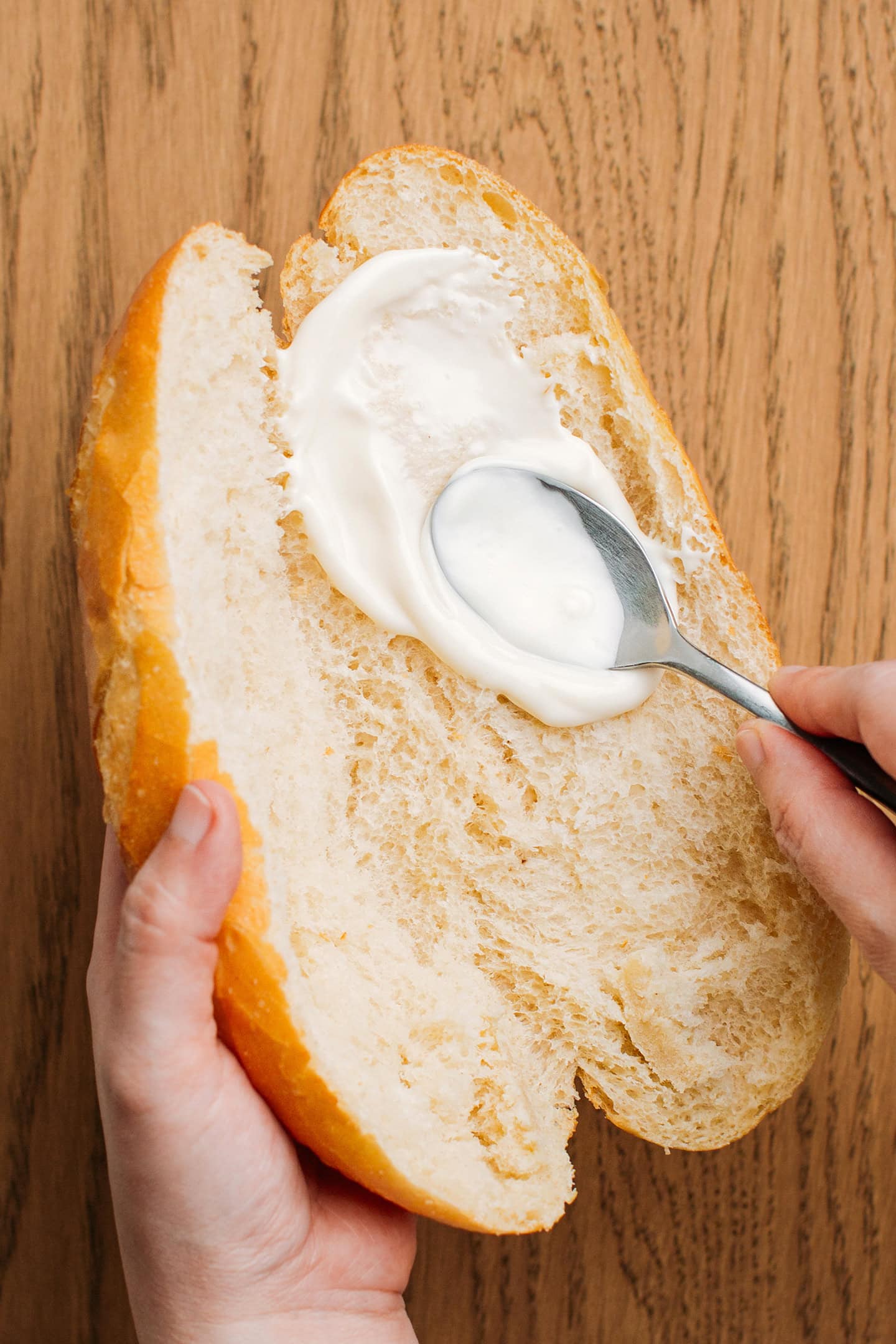 Spreading mayo inside a Vietnamese baguette.