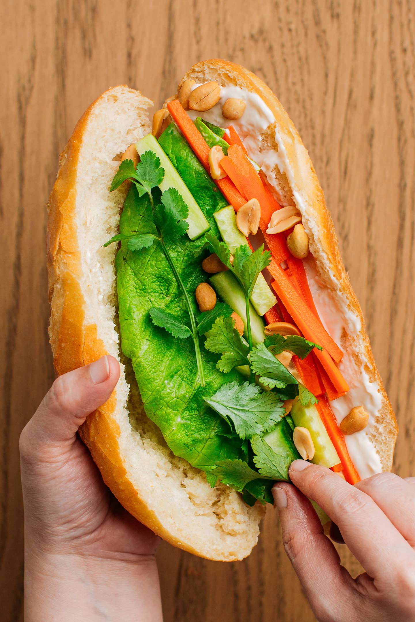 Placing cilantro into a banh mi sandwich.