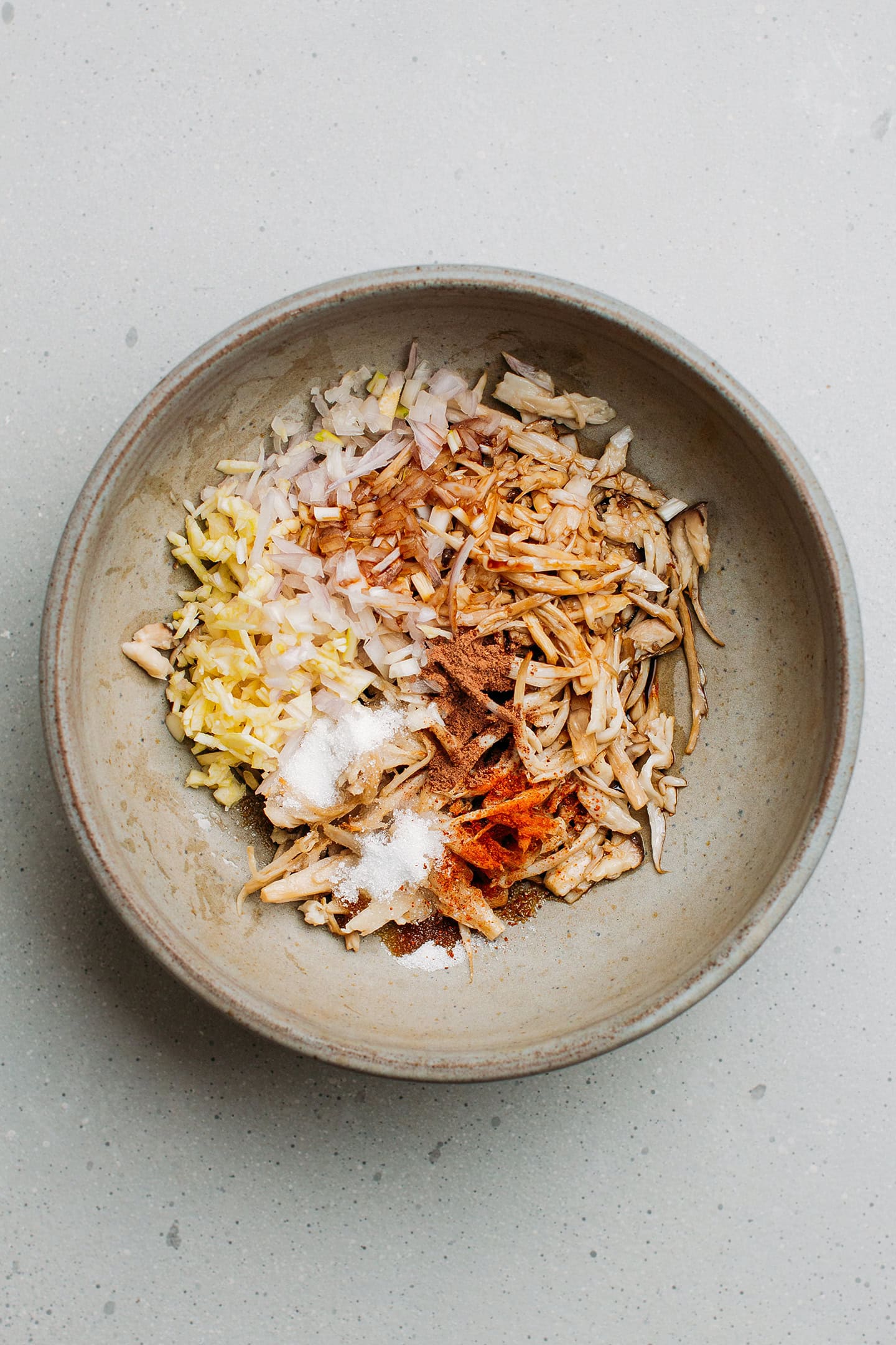 Pulled king oyster mushrooms, soy sauce, and five-spice powder in a bowl.